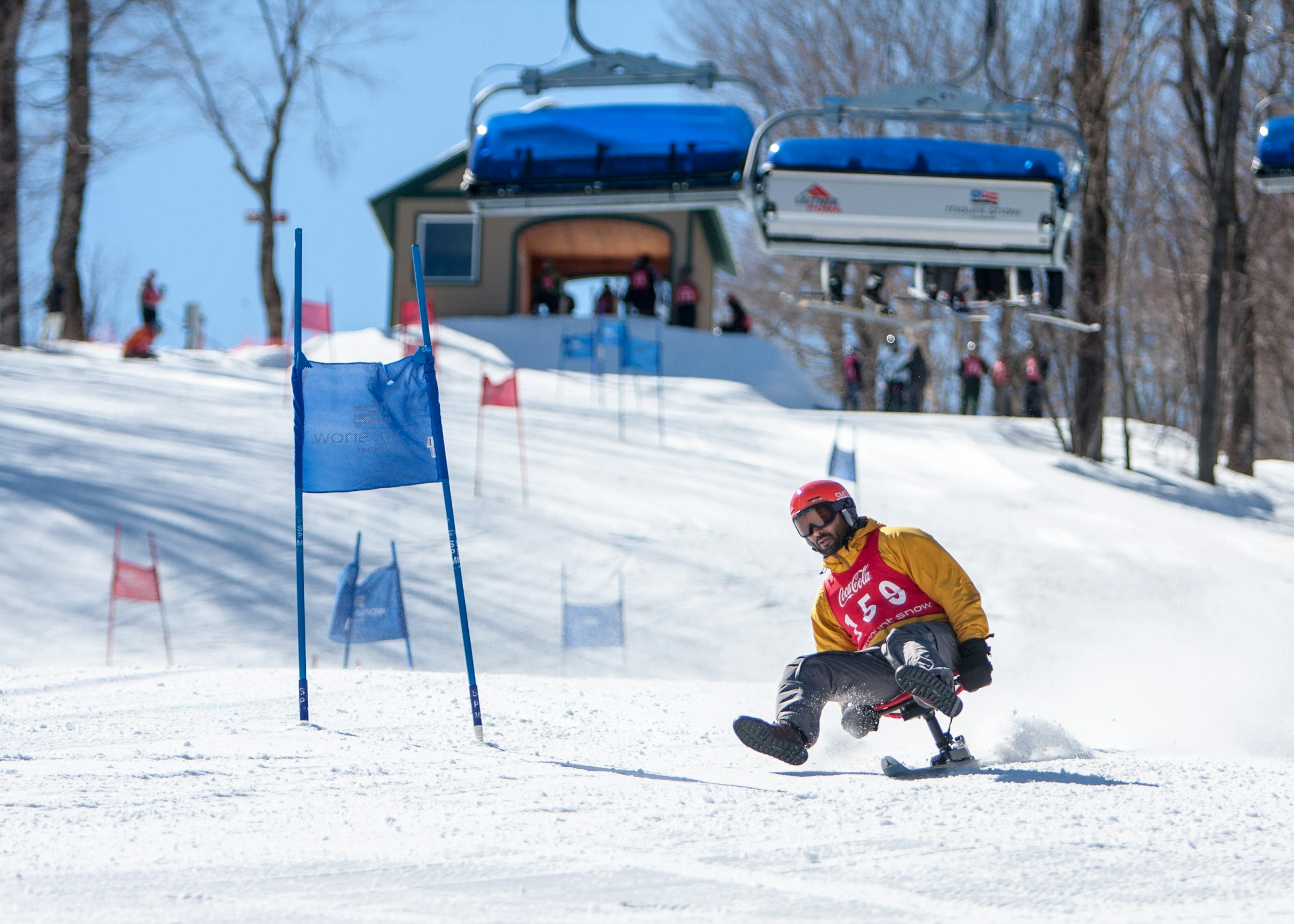 A man slides down a snowy hillside on a single ski, which he is sitting on like a chair; Unique sporting events