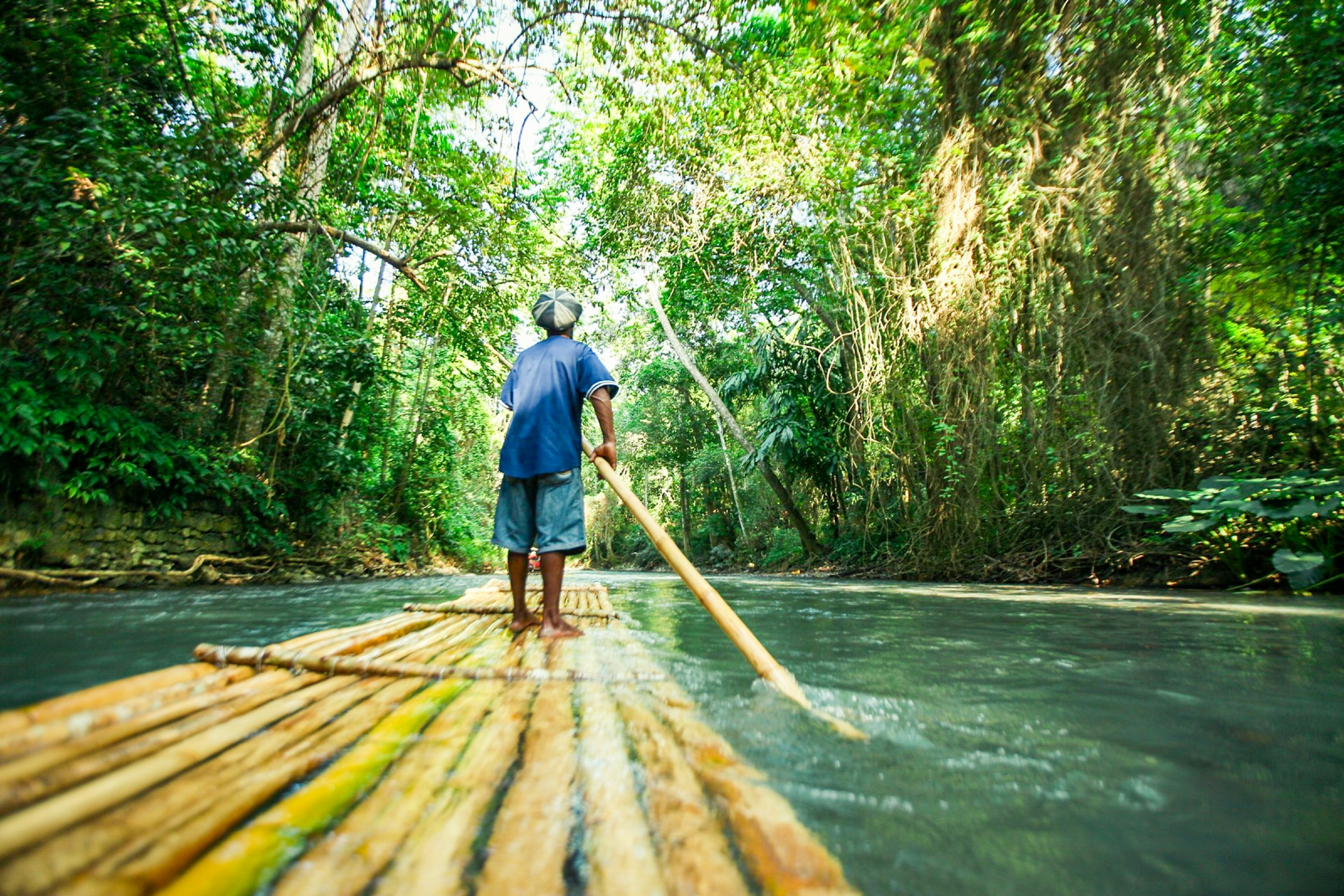 A man river rafting in the forest of Jamaica.