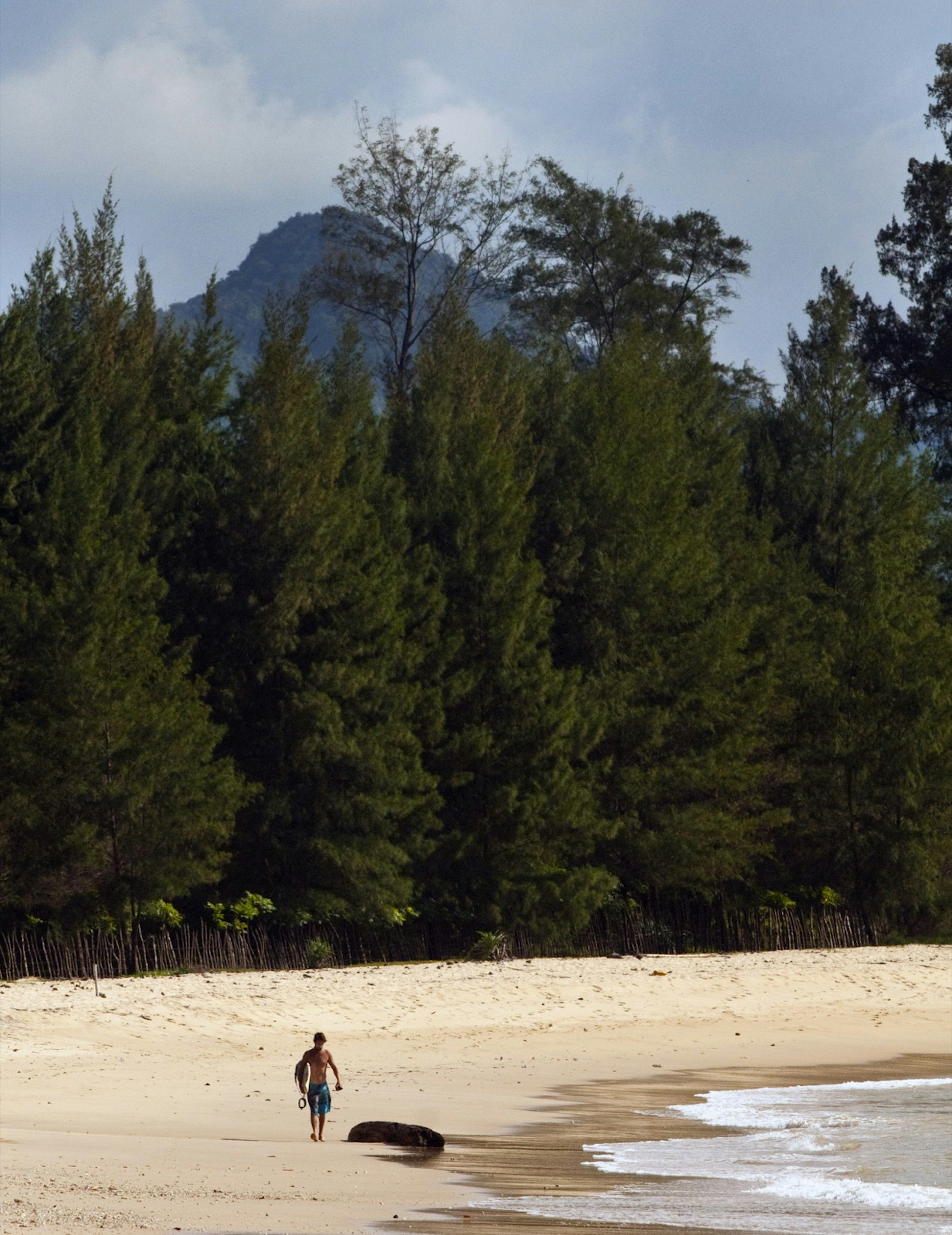 A solitary waves fan gets ready to surf on an island beach in Indonesia