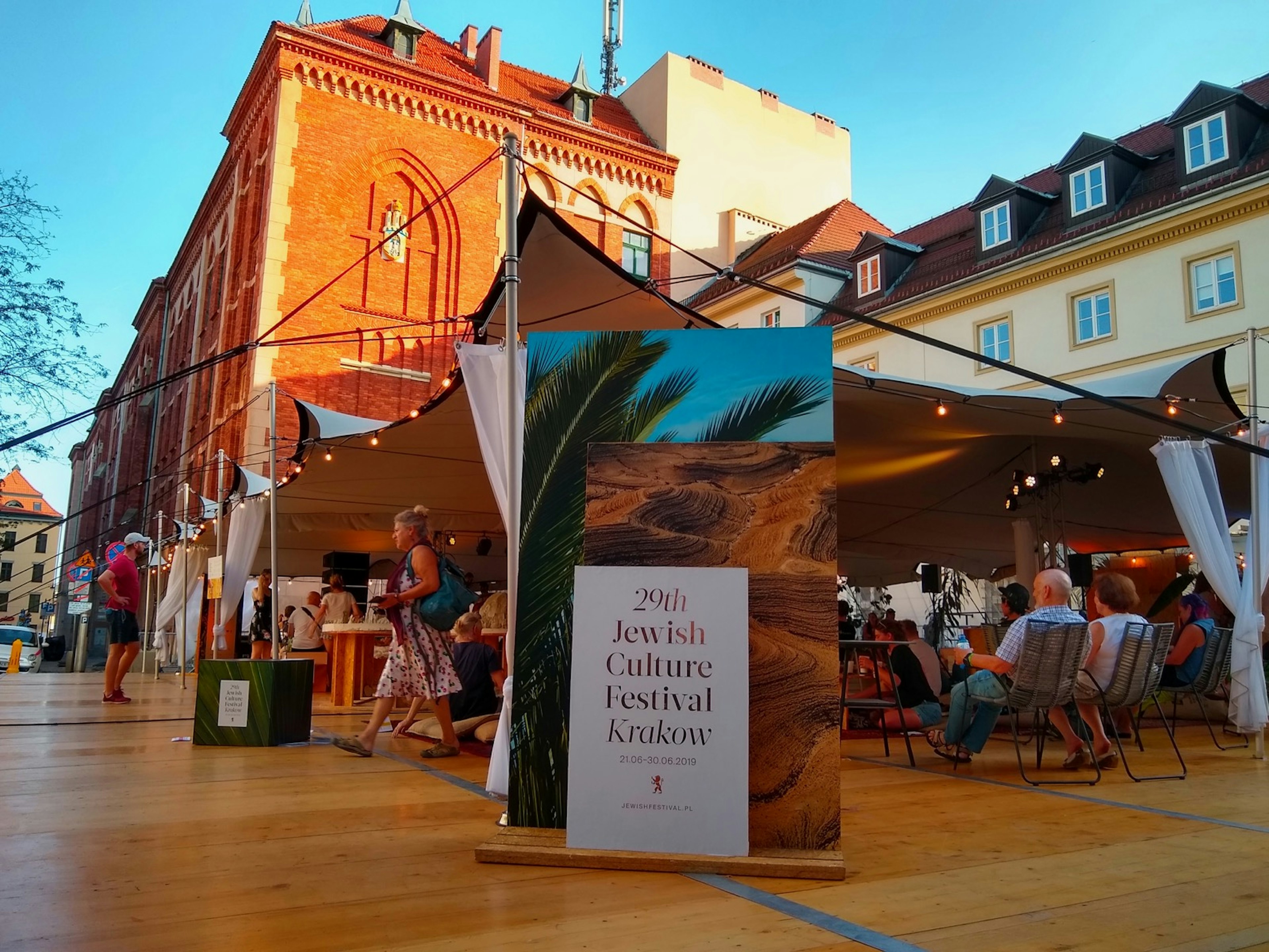 A display marks the Jewish Cultural Festival in front of a tent filled with people; Krakow Jewish Cultural revival