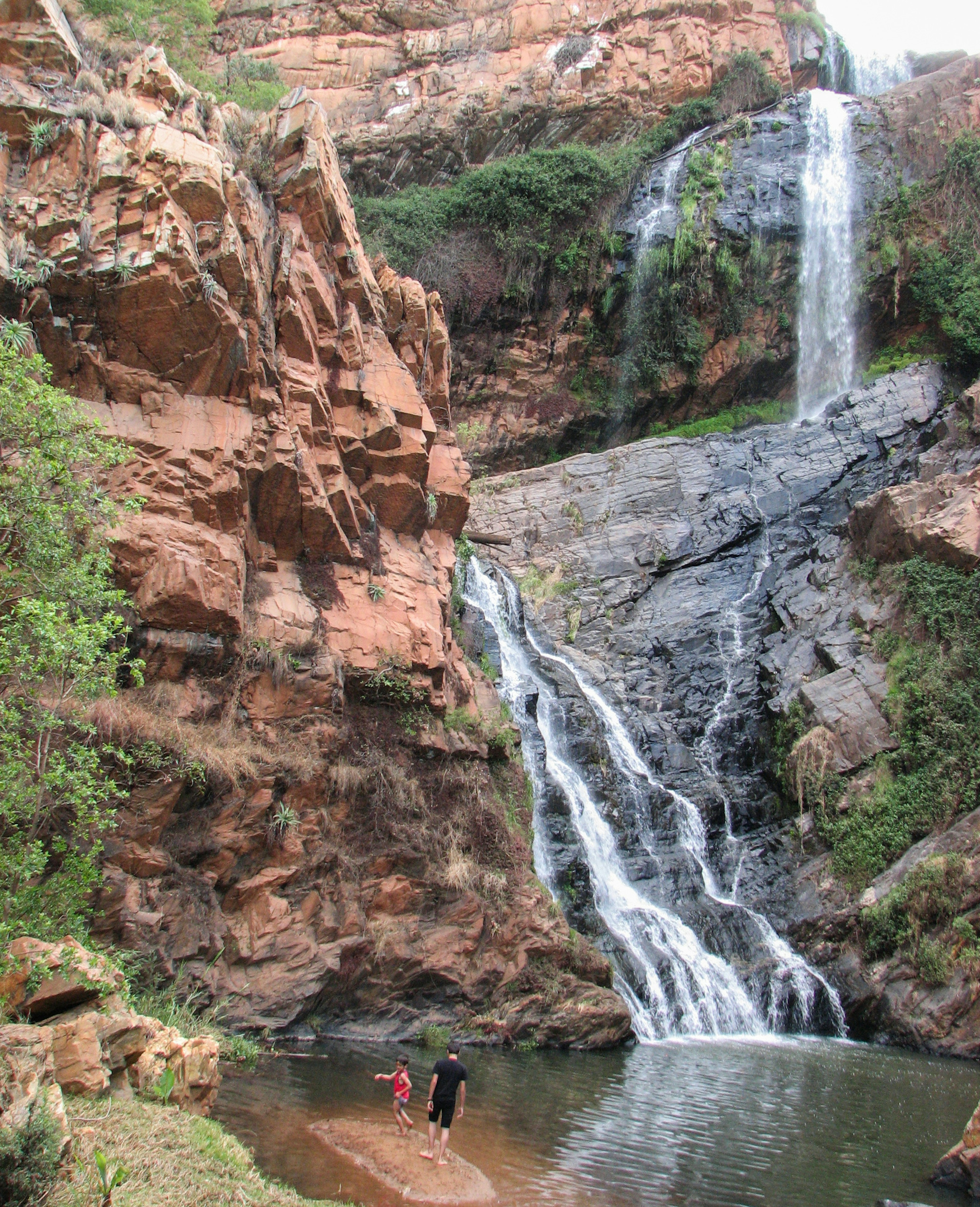 Green trees stand in contrast to bright red rock cliffs, with water cascading down the rockface at an oblique angle © Heather Mason / ϰϲʿ¼