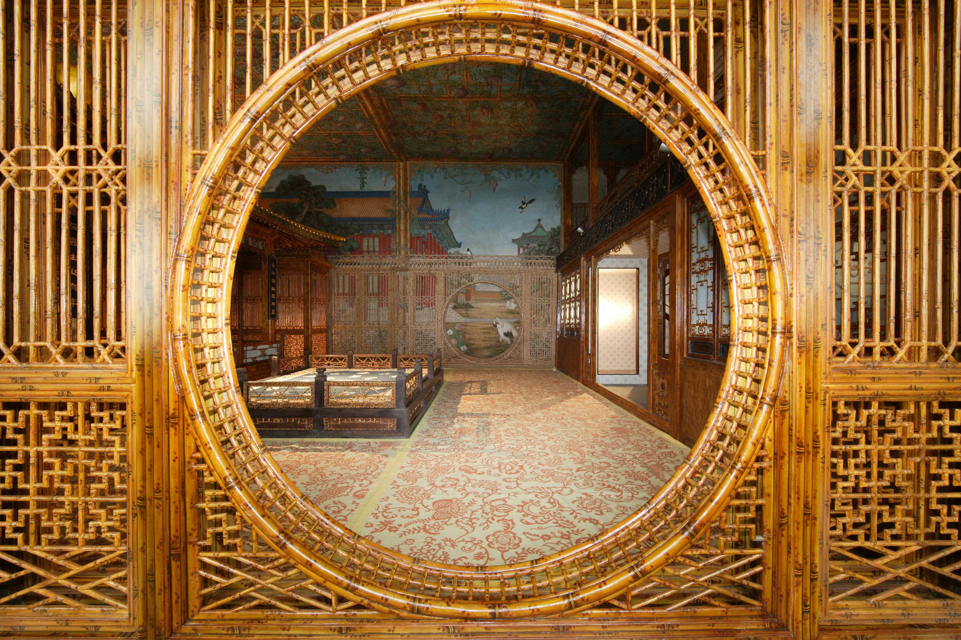 An ornately carved wall with a circular window at the Qianlong Garden.