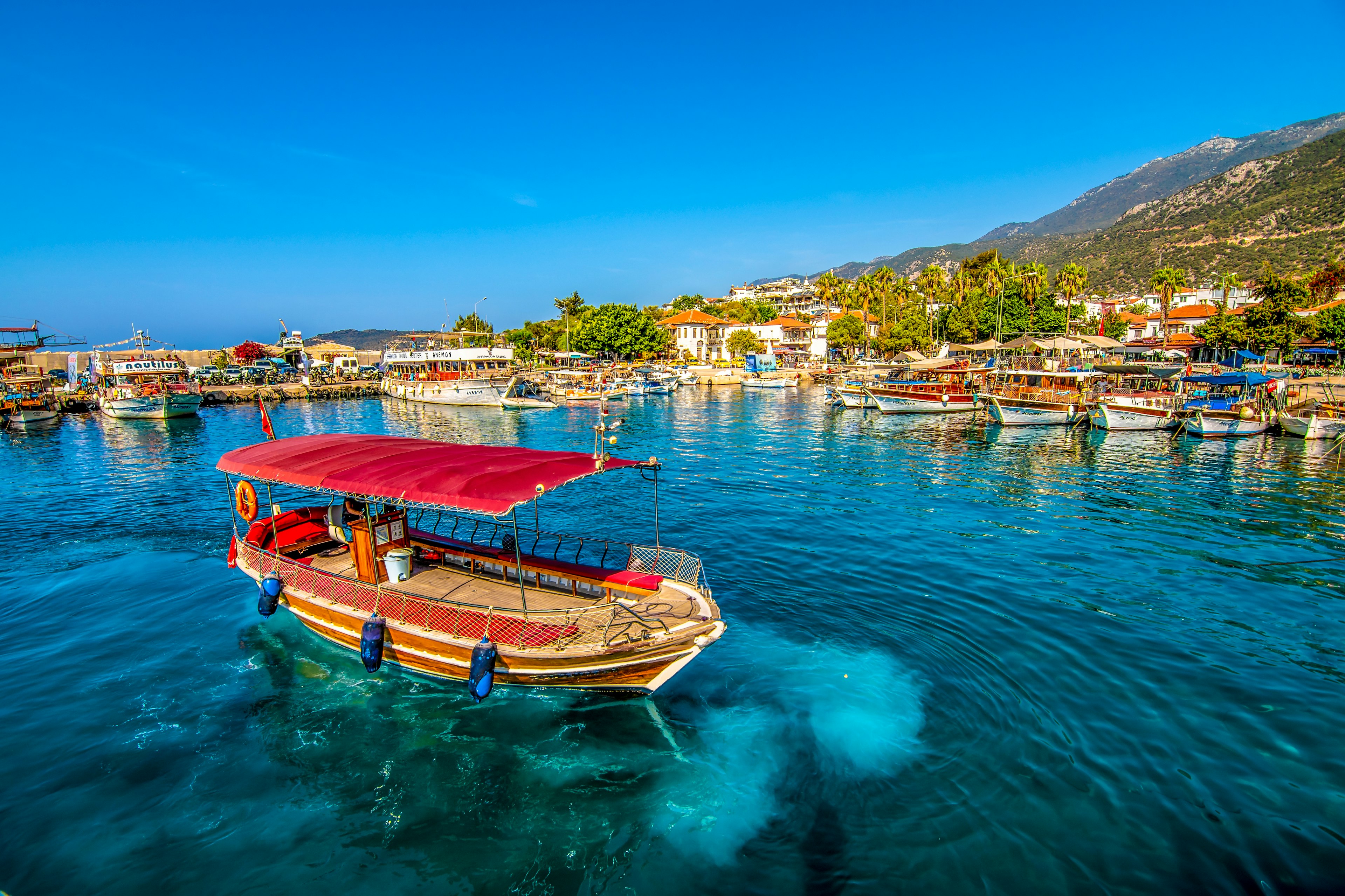 Kas harbour lined with boats and with bars along the harbour's edge.