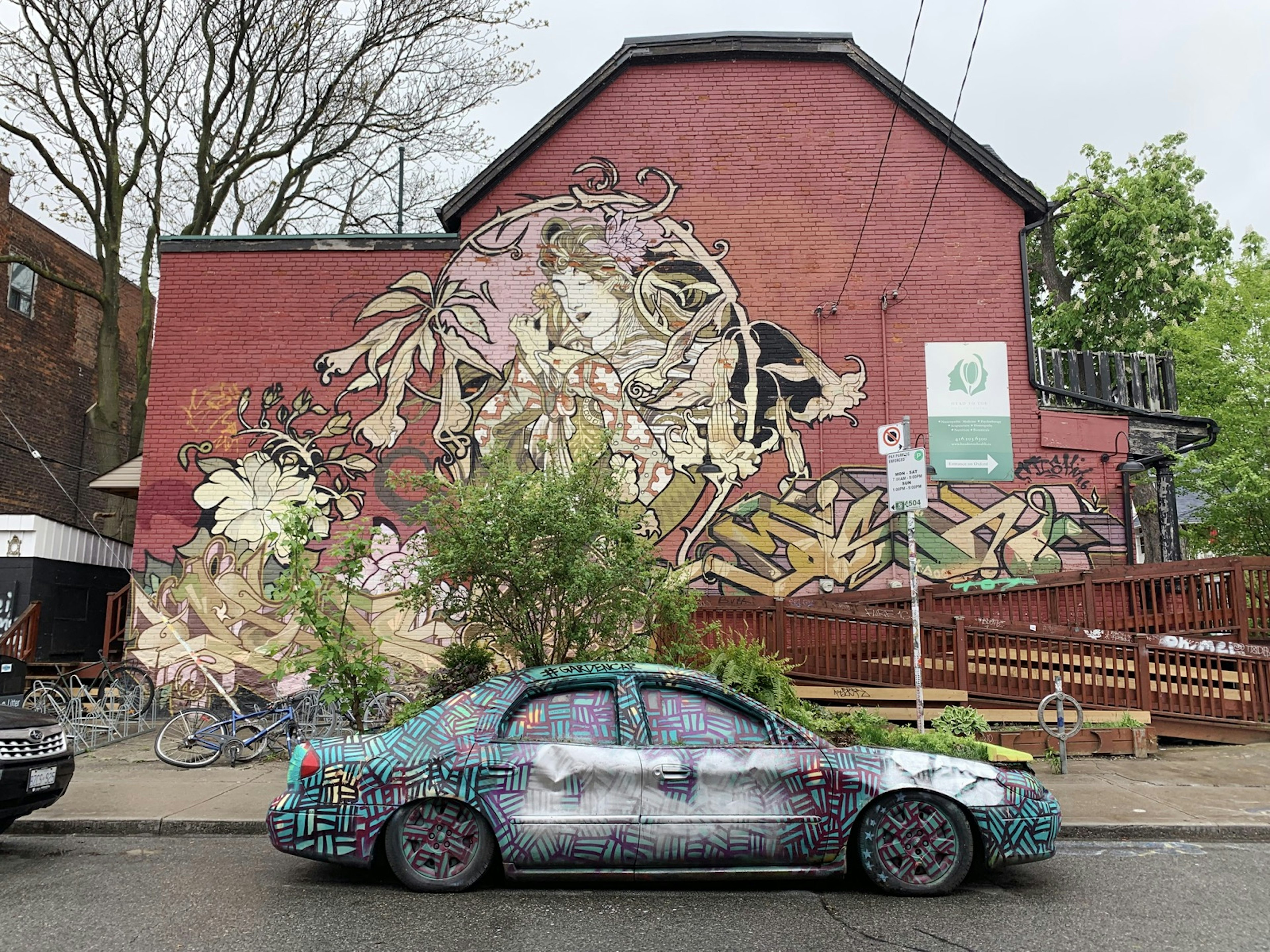 An art nouveau mural and a psychadelic colored car are seen in the trendy neighborhood of Kensington in Toronto