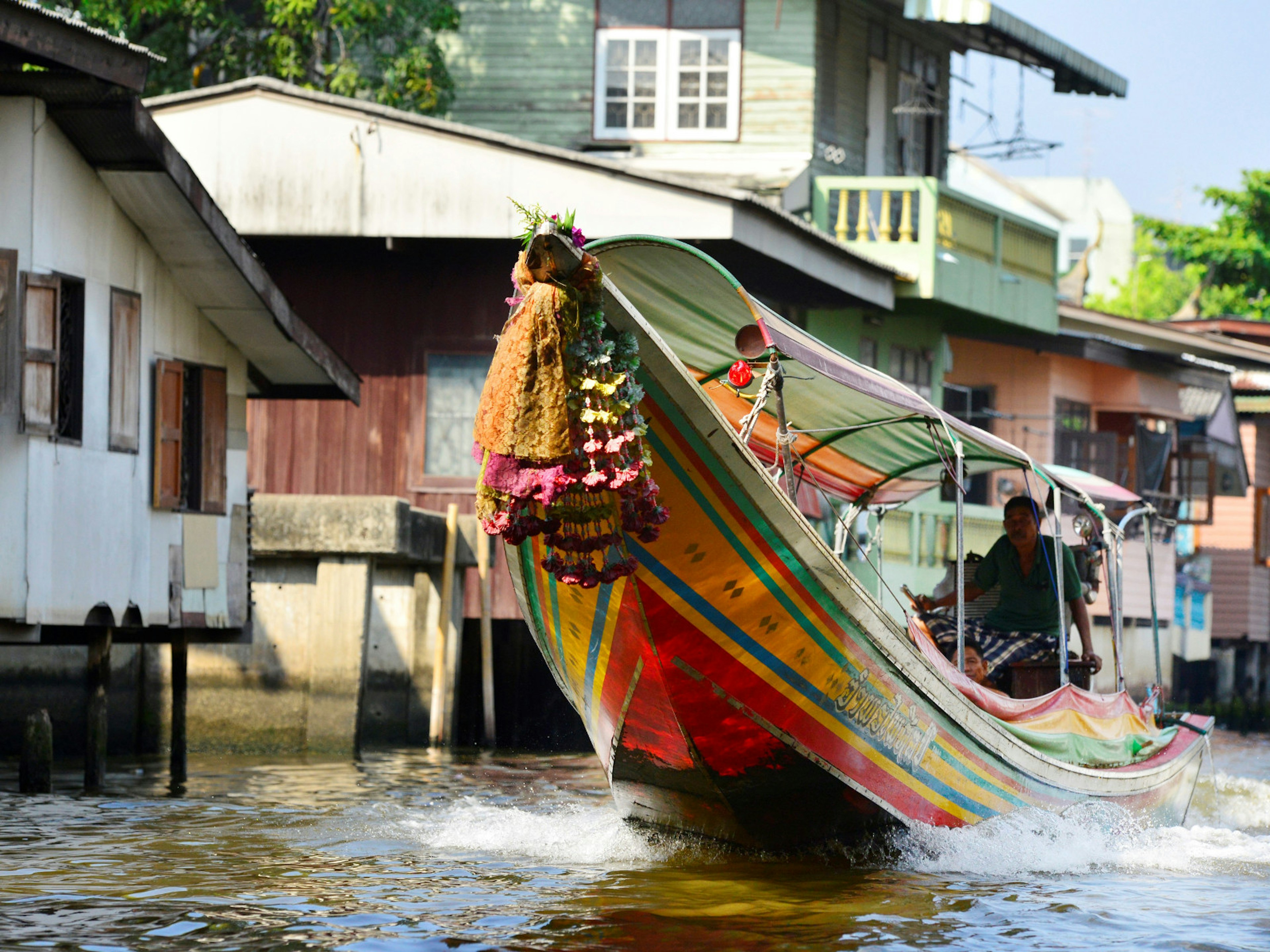 A colourful longtail boat glides along the Khlong Mon canal in Bangkok