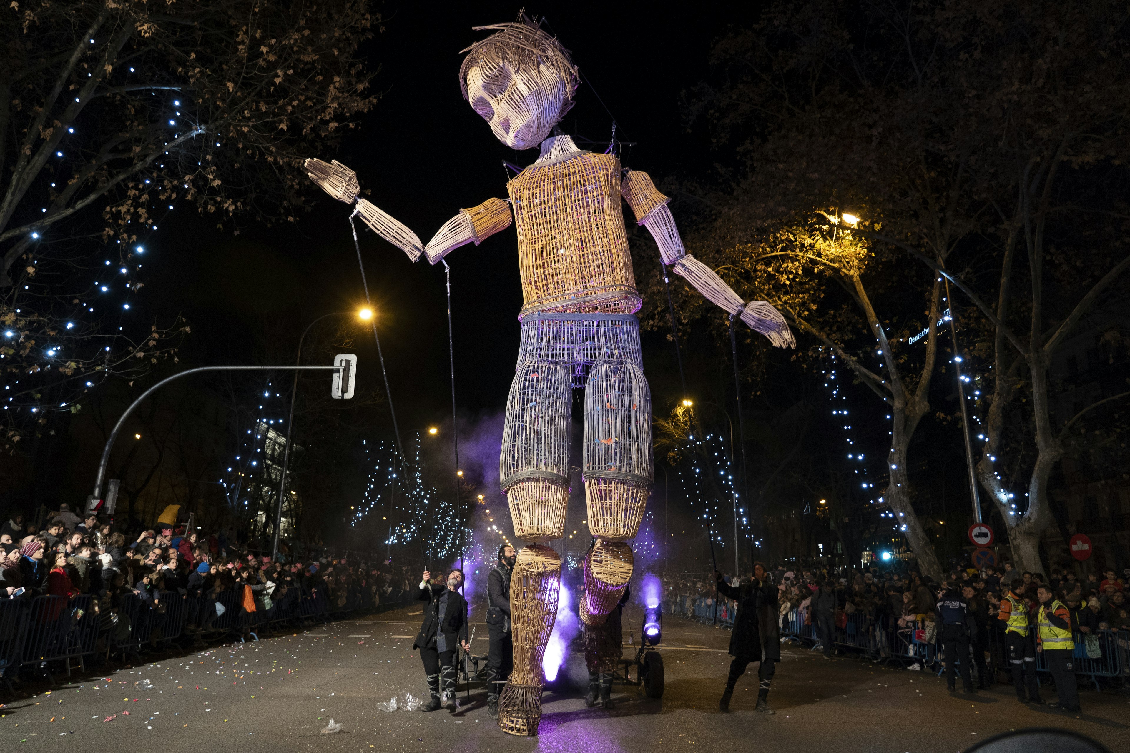 A giant puppet makes its way through the Kings' Day parade in Madrid, controlled by men pulling on wires far below.