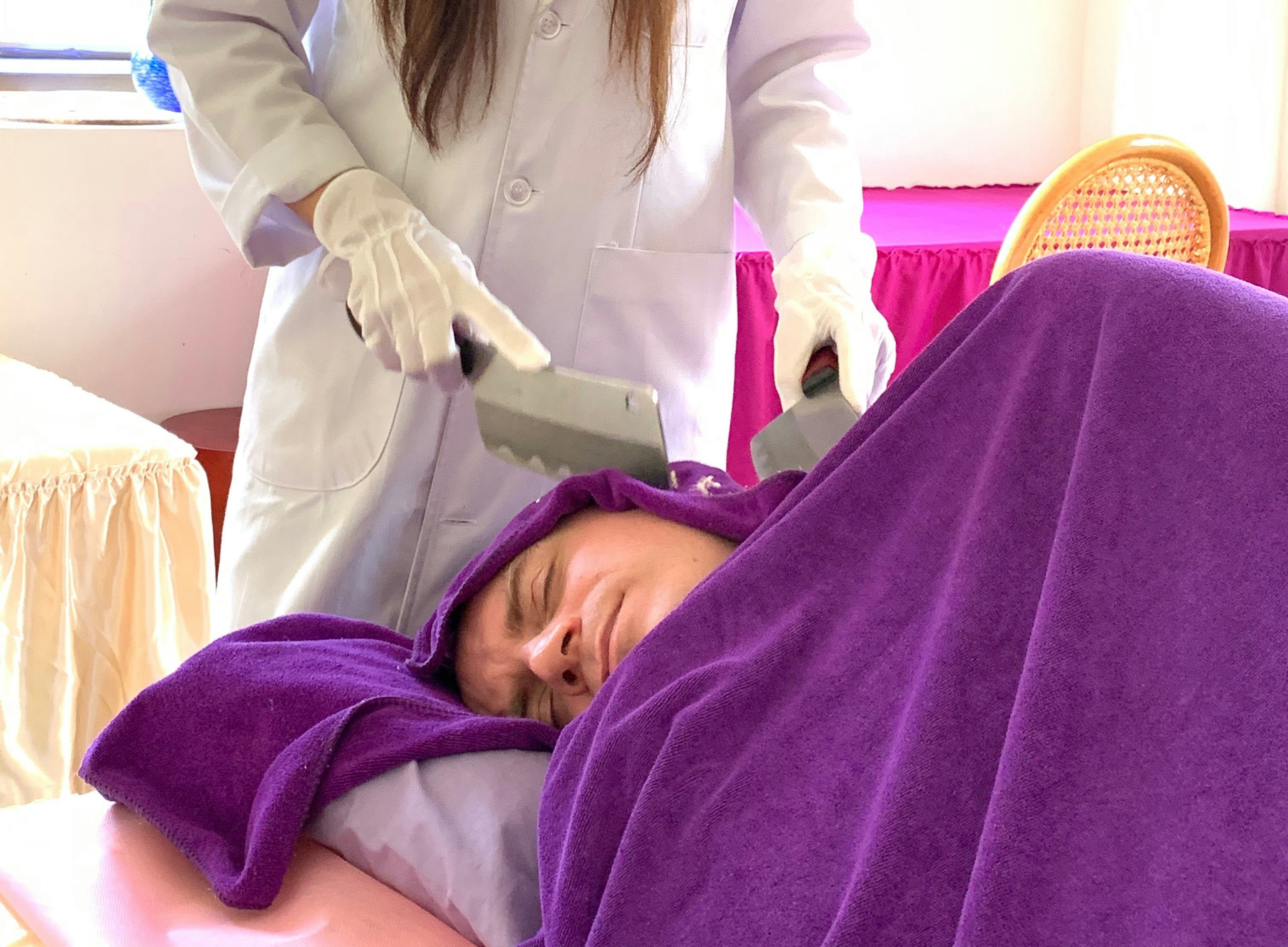 The author has his head massaged by two knives, while being wrapped in a purple towel.