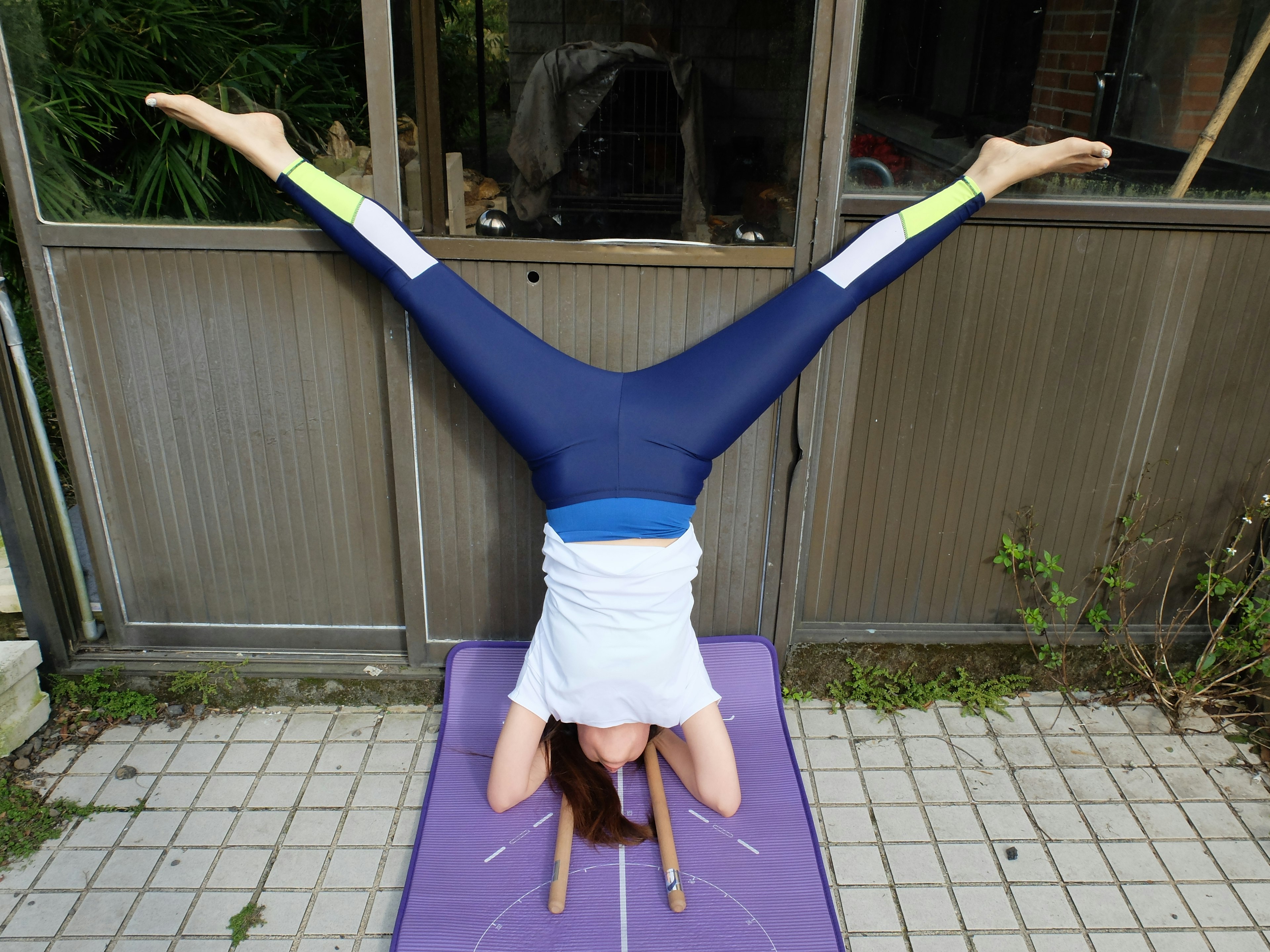 Hsiao Mei-Fang performs an acrobatic headstand on a purple mat.