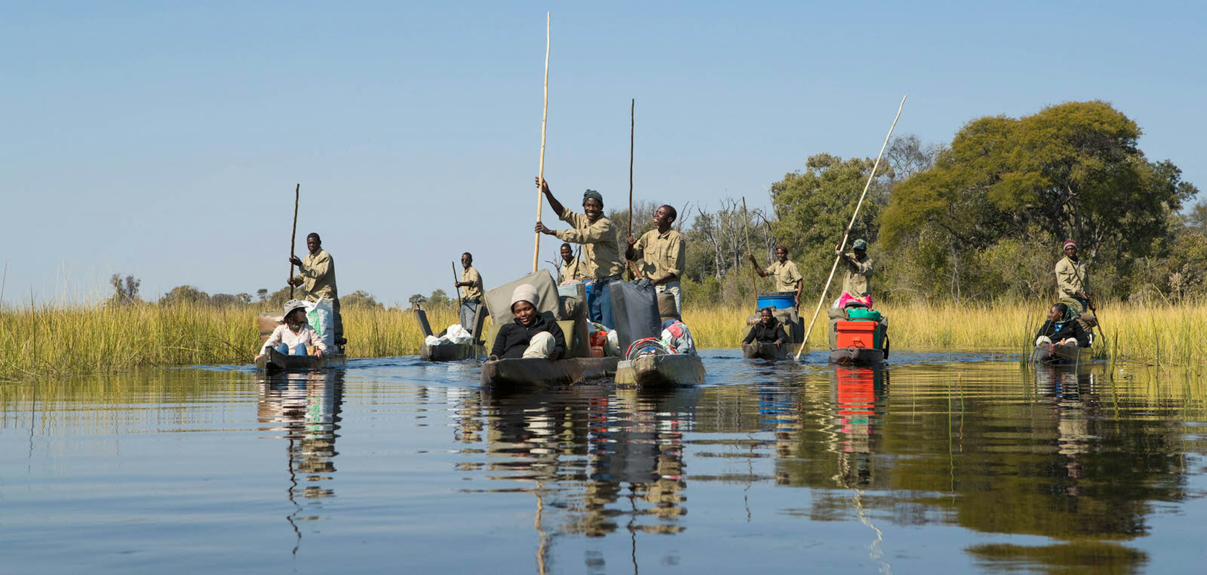 Half a dozen mokoro (traditional dugout canoes) moving through the Okavango Delta