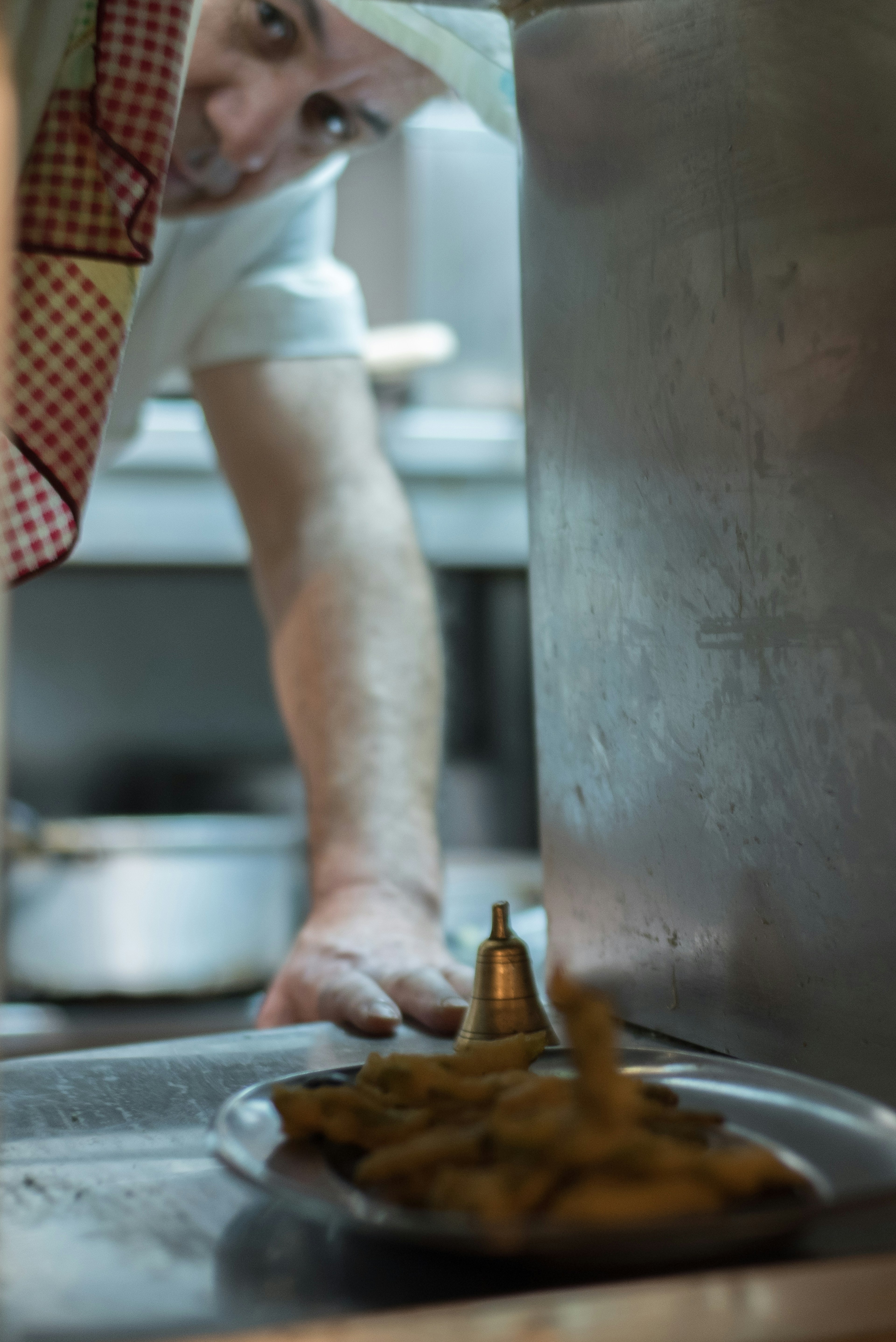 A plate of peixinhis da horta waiting in the pass while the chef looks out through the small service hole