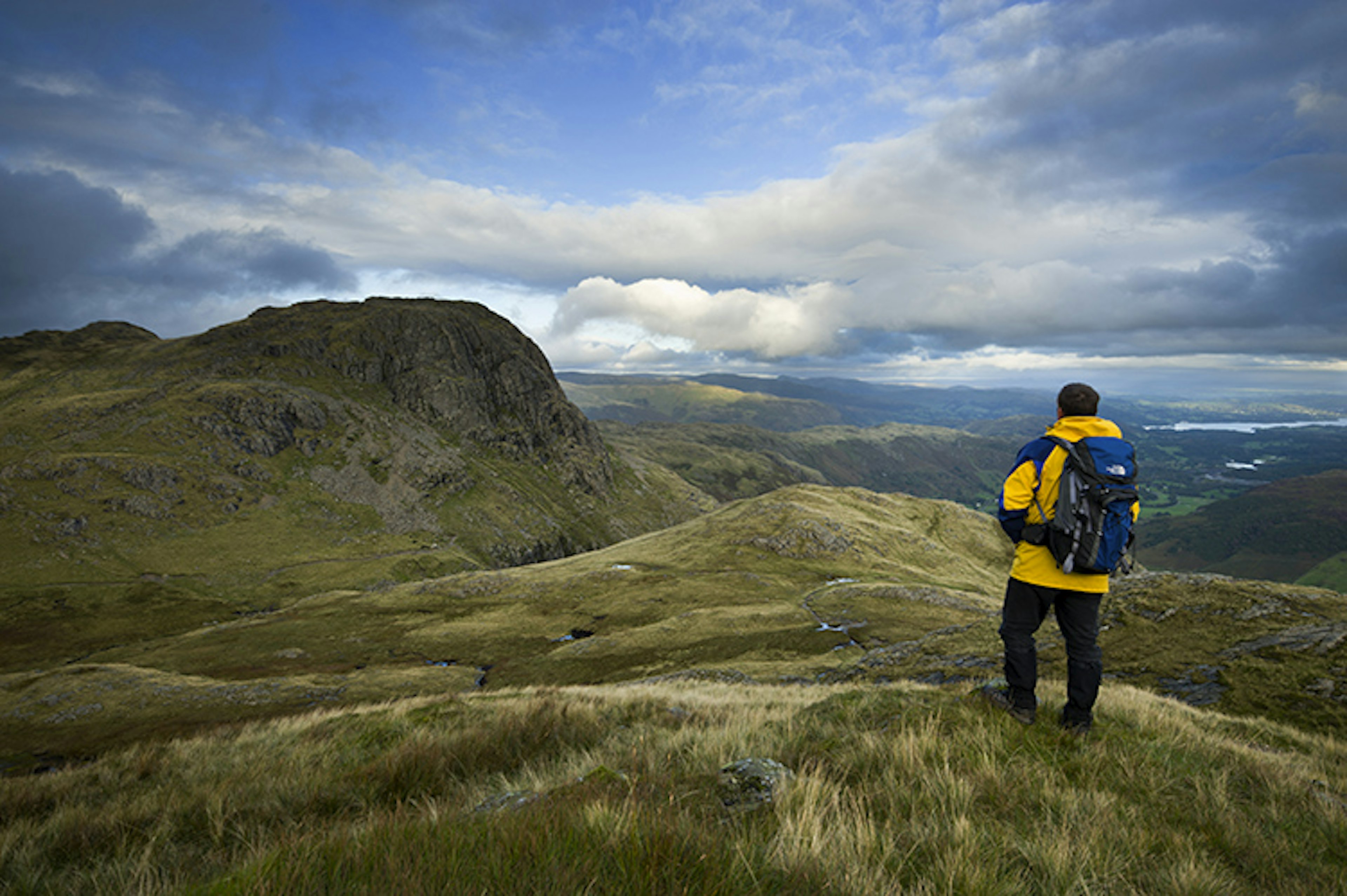 Hiker standing on Loft Crag looking towards Harrison Stickle, Langdale Pikes.