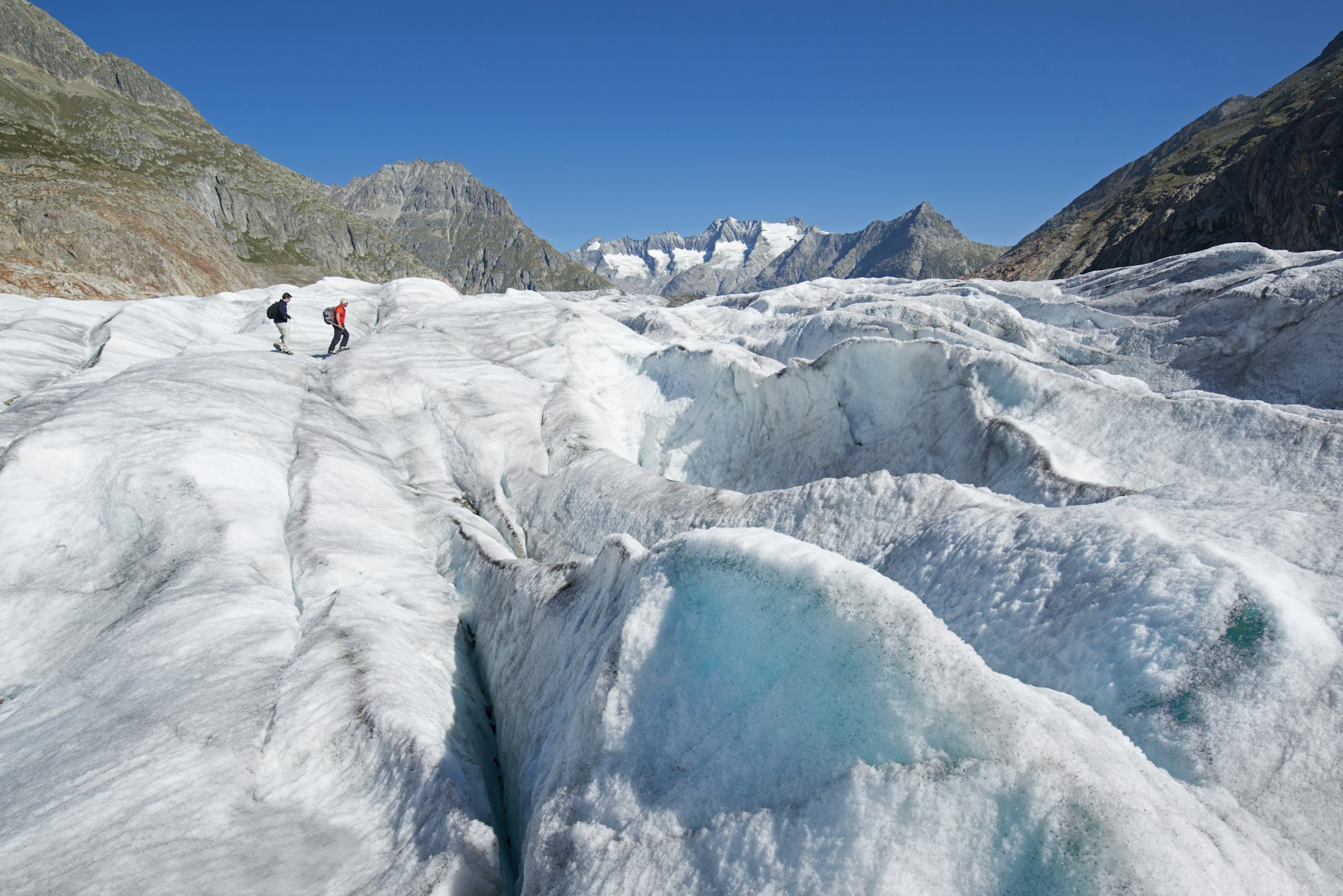 Two trekkers walking on Aletsch Glacier, Valais, Switzerland