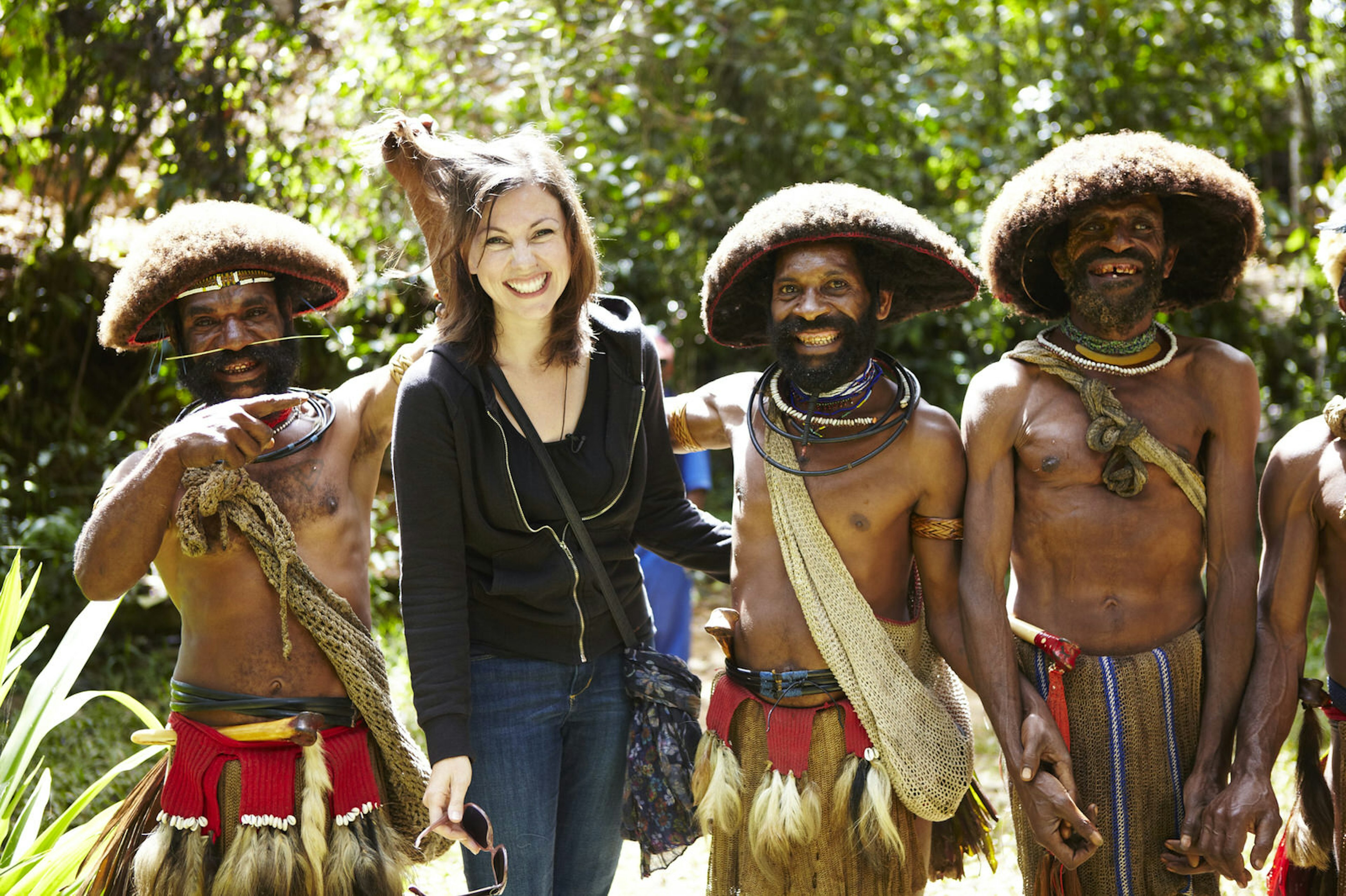 A woman poses for a photo with a trio of Huli Wigmen in the Tari region.