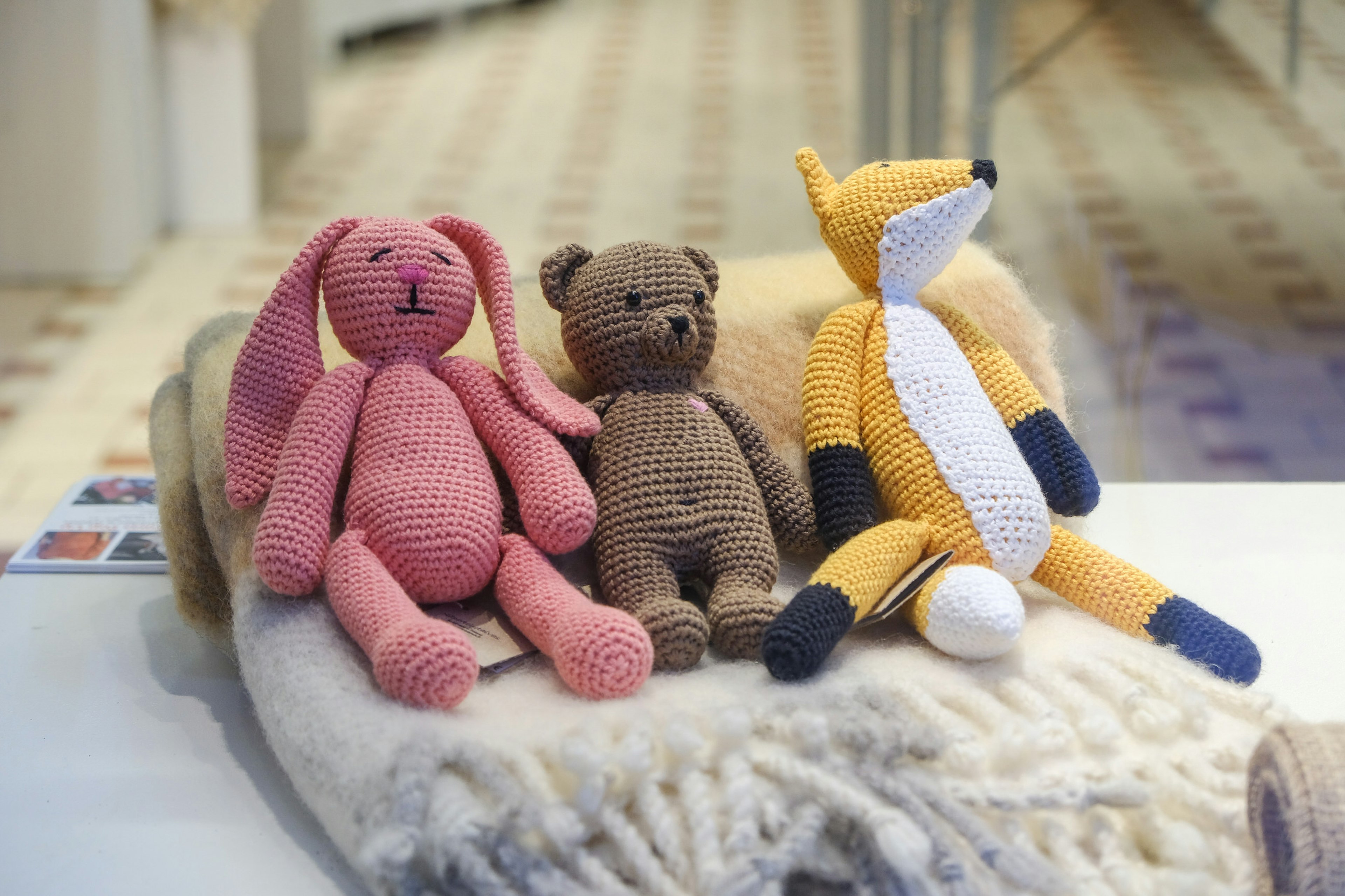 Three knitted toys – a rabbit, a bear and a fox – lined up against a rolled-up scarf © Tim Bird / ϰϲʿ¼