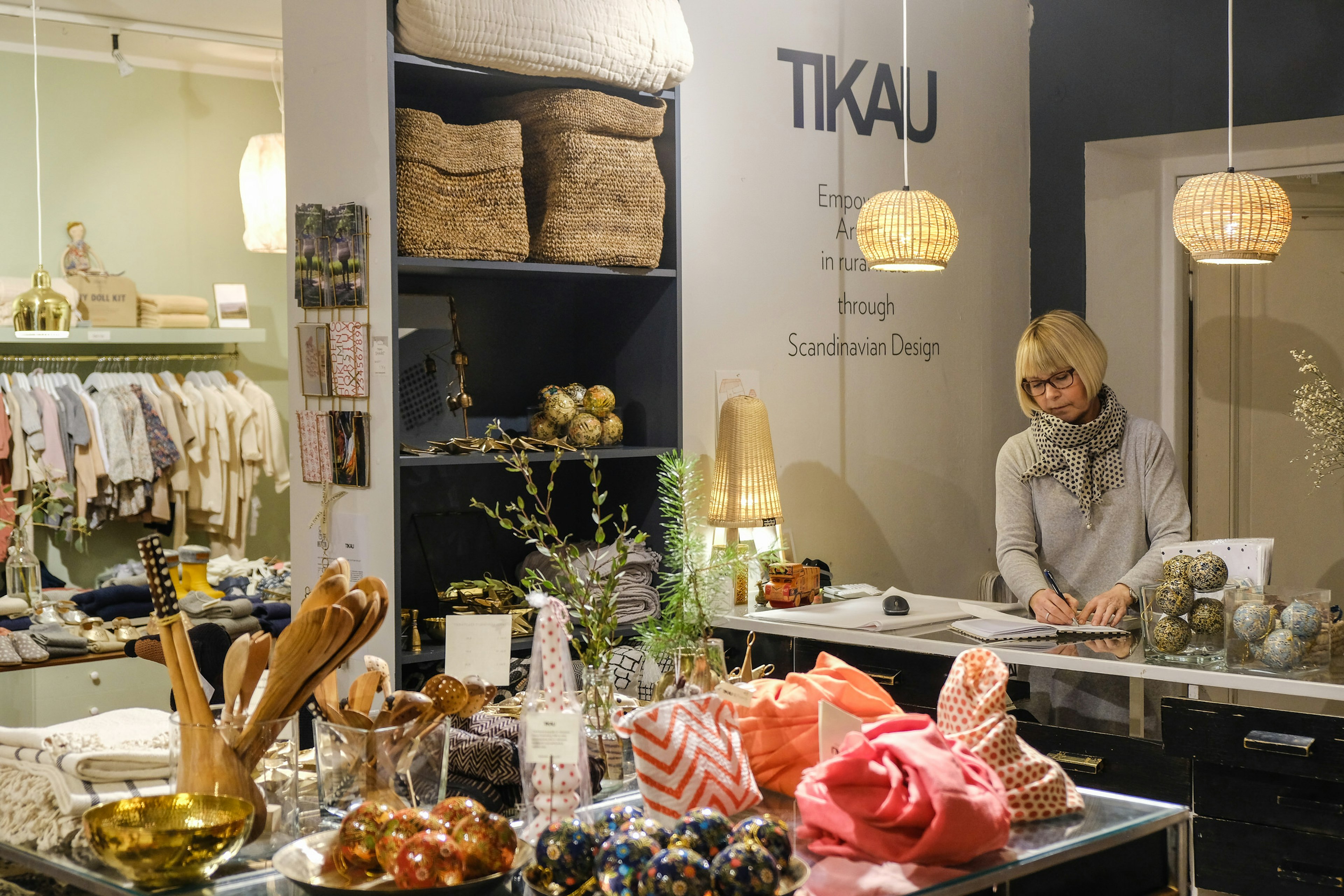 A sales assistant stands behind the counter of the Tikau store, Helsinki, with display of hand-made items in the foreground © Tim Bird / Lonely Planet