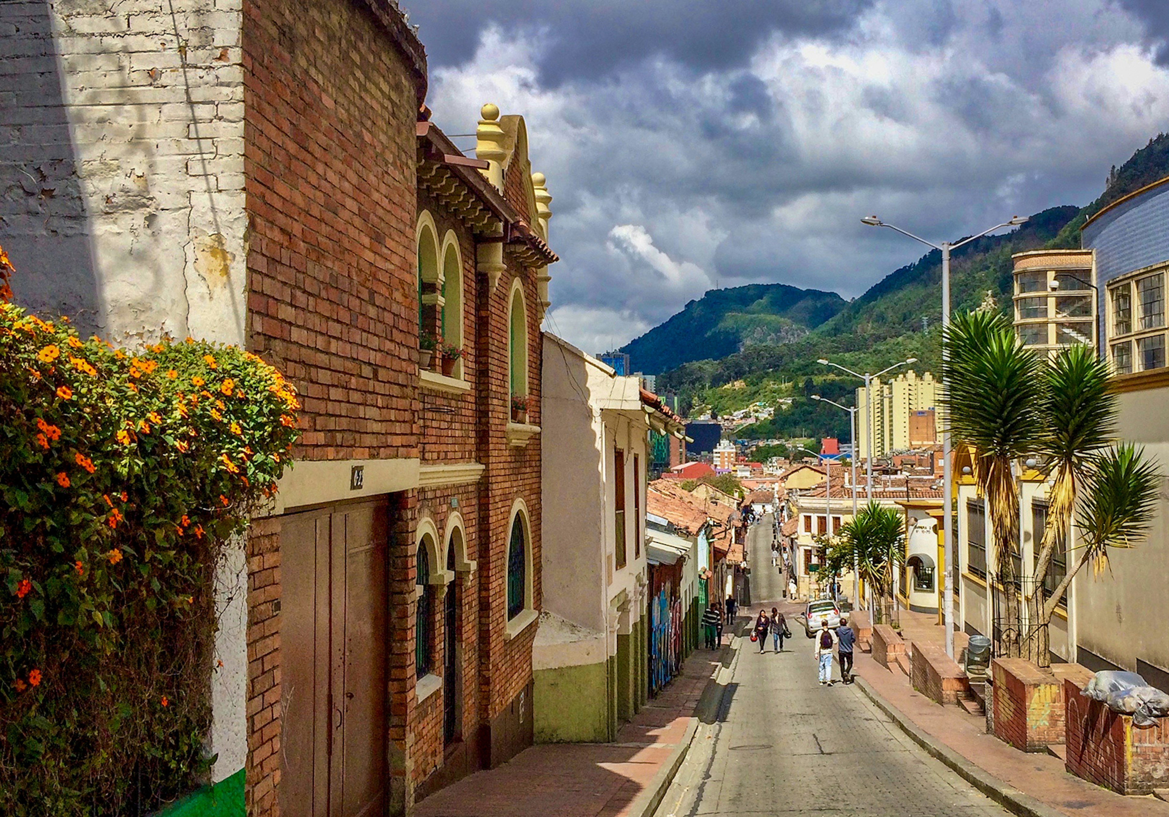 A photo of a street lined with historic buildings, heading towards green hills in the background