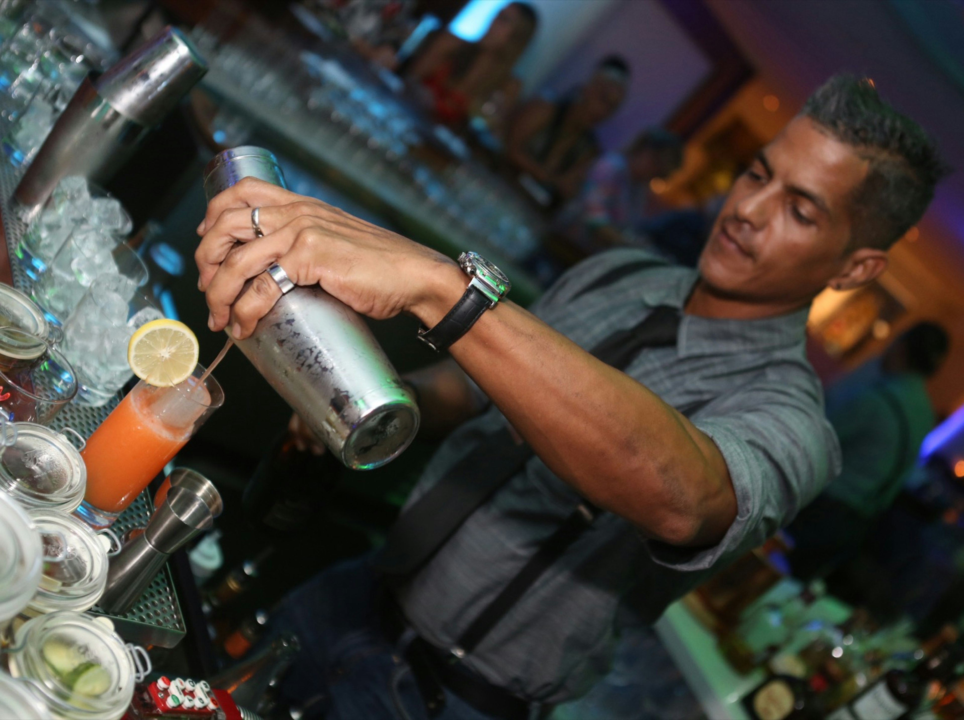 A bartender pours a cocktail into a glass at a bar in La Concha in San Juan