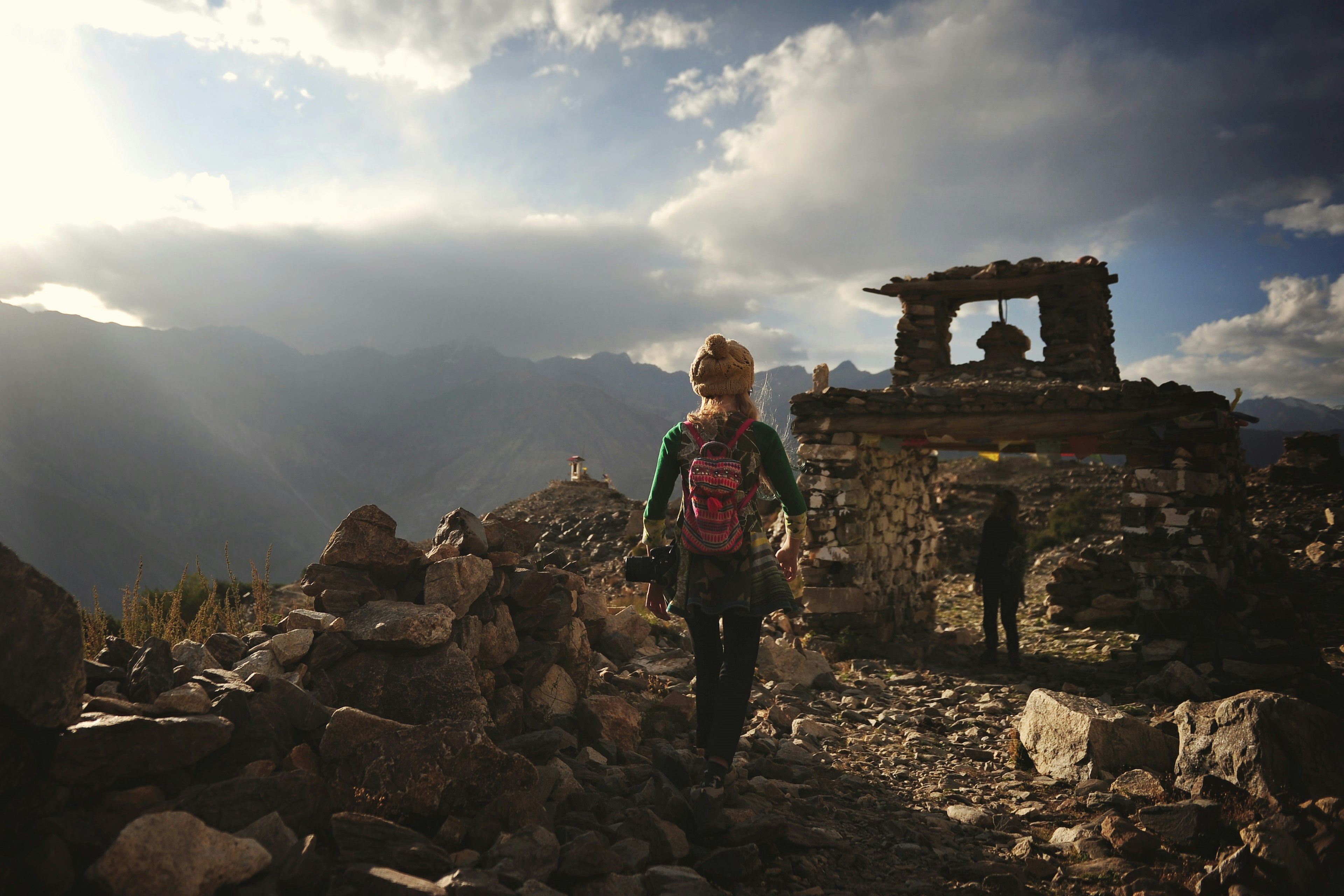 A young girl with her back to the camera is hiking in Ladakh, India, over rocky terrain