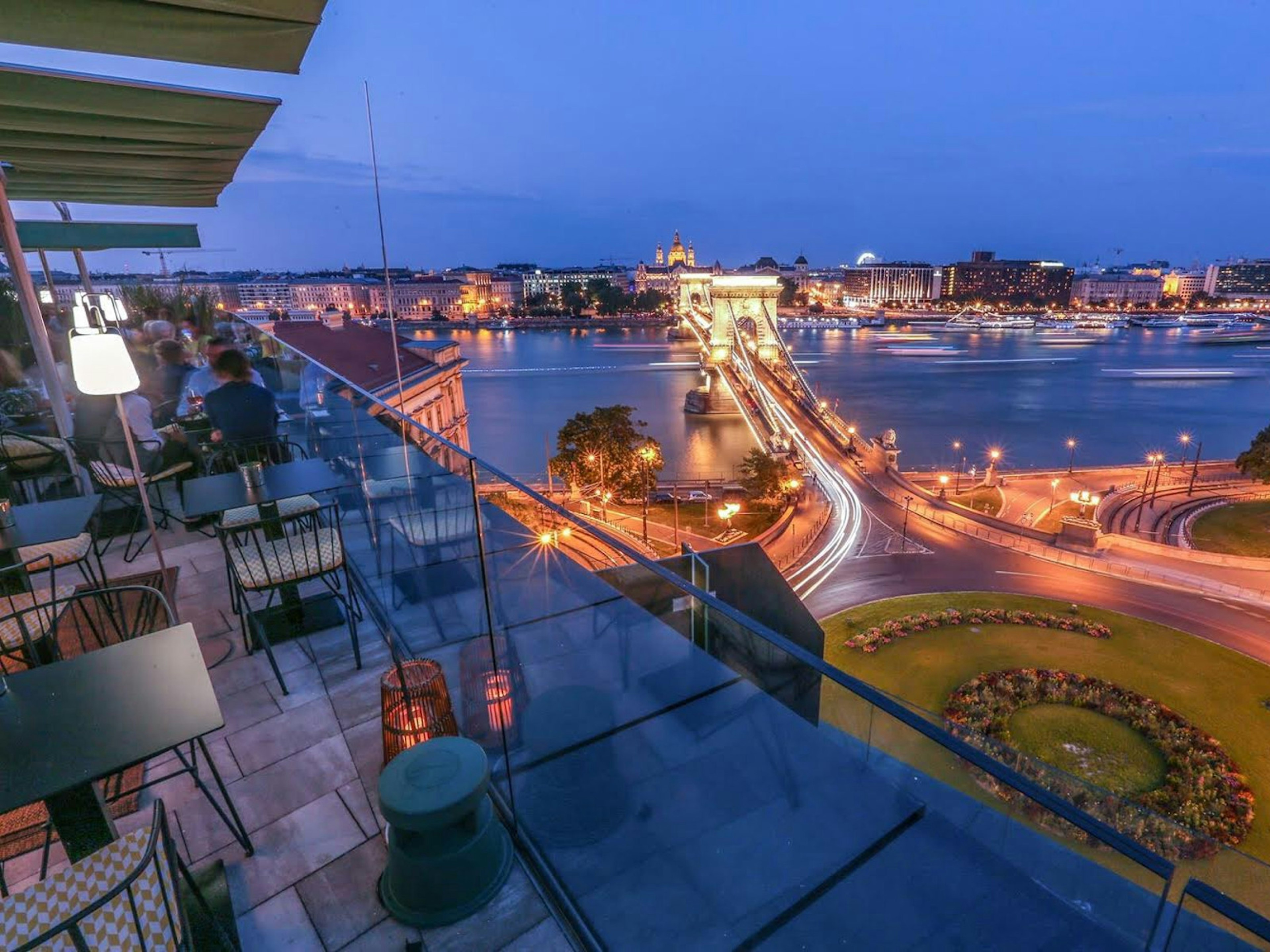 People enjoying the nighttime view of Széchenyi Bridge from Leo rooftop bar in Budapest