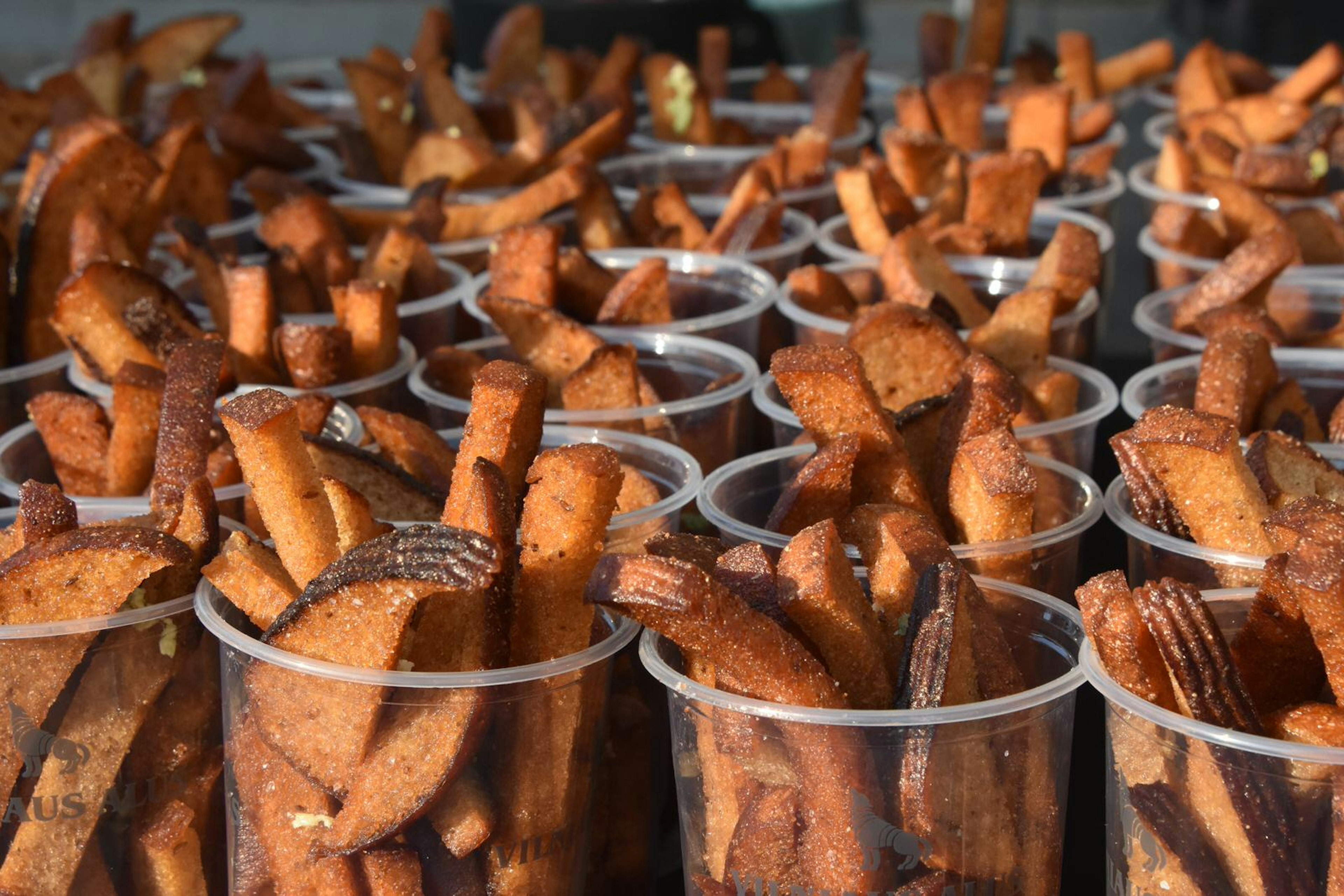 Cups and cups of beer sticks (charred rye bread fried in garlic and sesame seeds) stand on a counter top