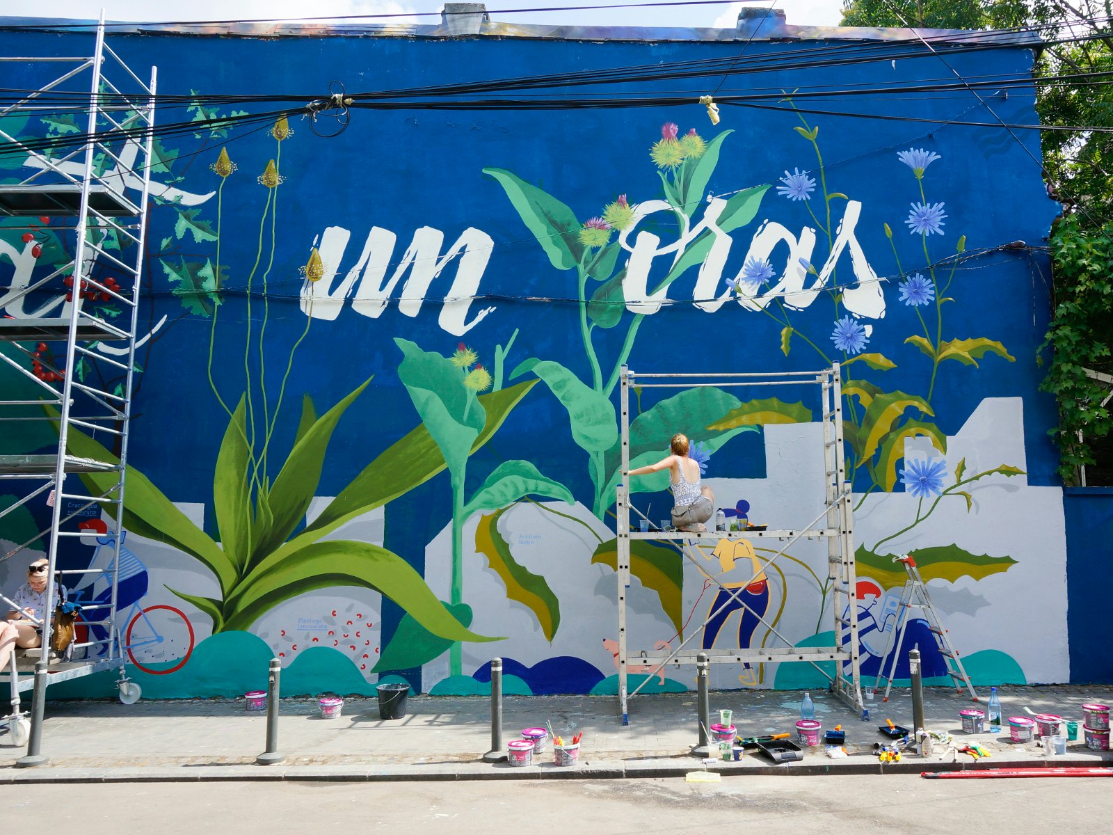 A girl painting a large street mural in Bucharest