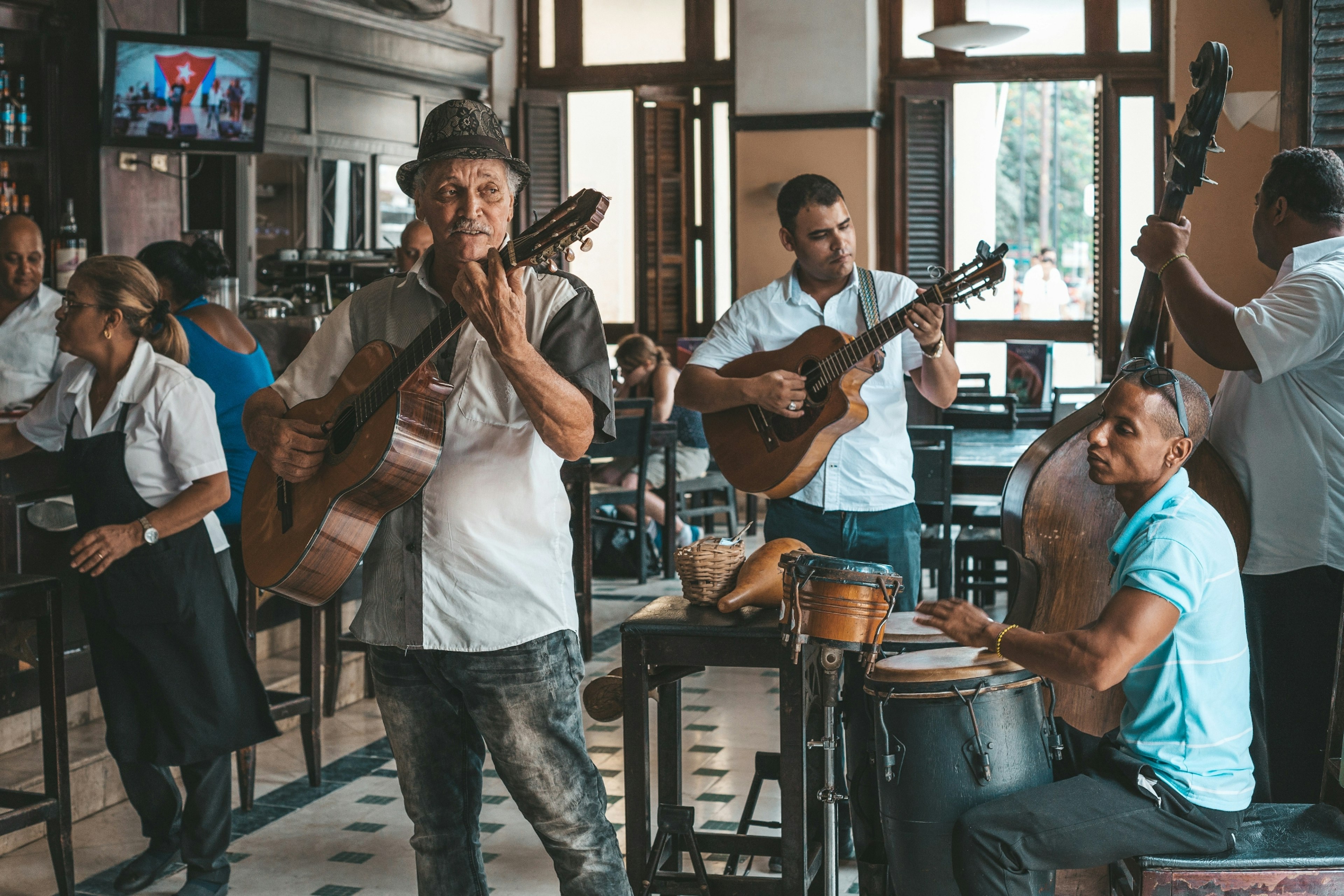 A local four-piece band play in a restaurant in Havana, Cuba. Two of the musicians play guitar, one plays bass and one plays drums.