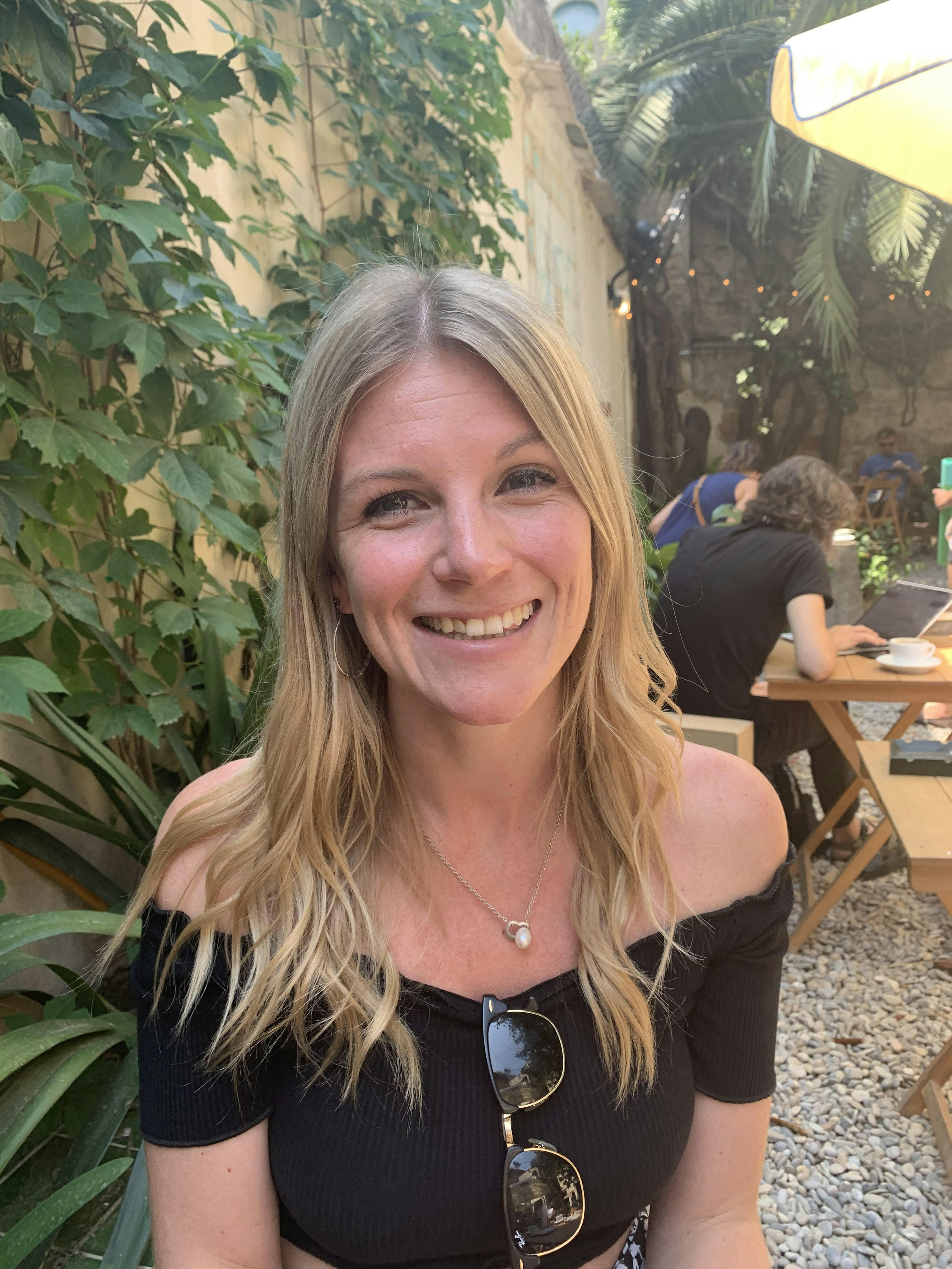 Writer Isabella Noble sitting in a restaurant's leafy courtyard garden.