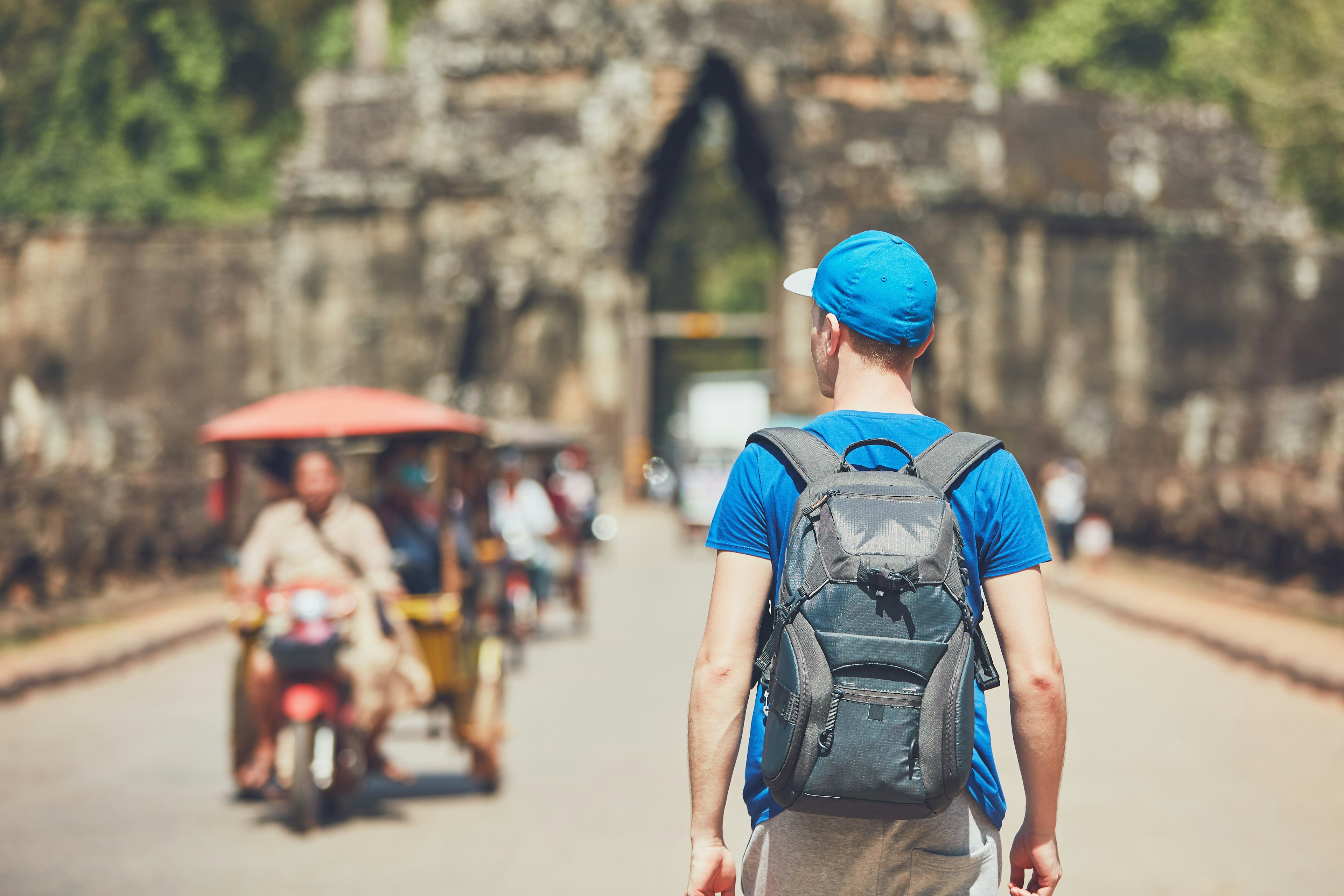 A young male walks in front of the ancient structures of Angkor Wat.