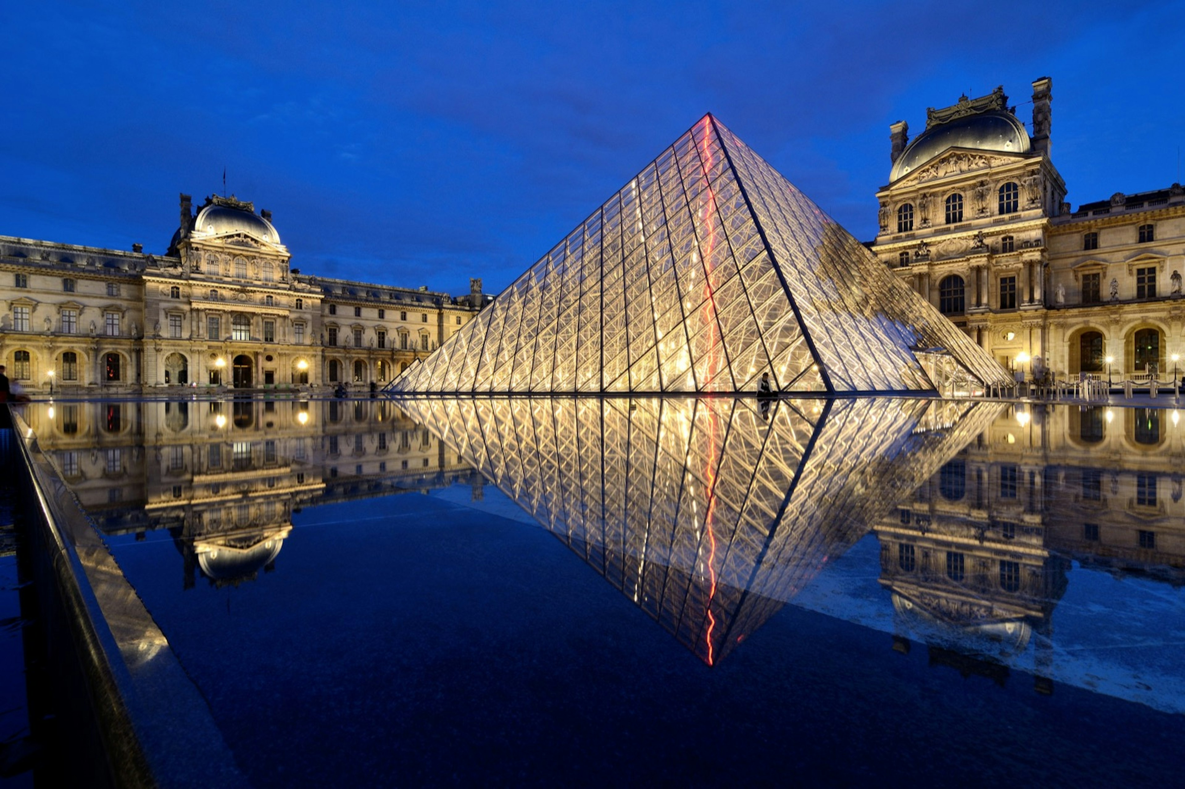 The Grande Pyramide is lit up at night in front of the Louvre's main buildings