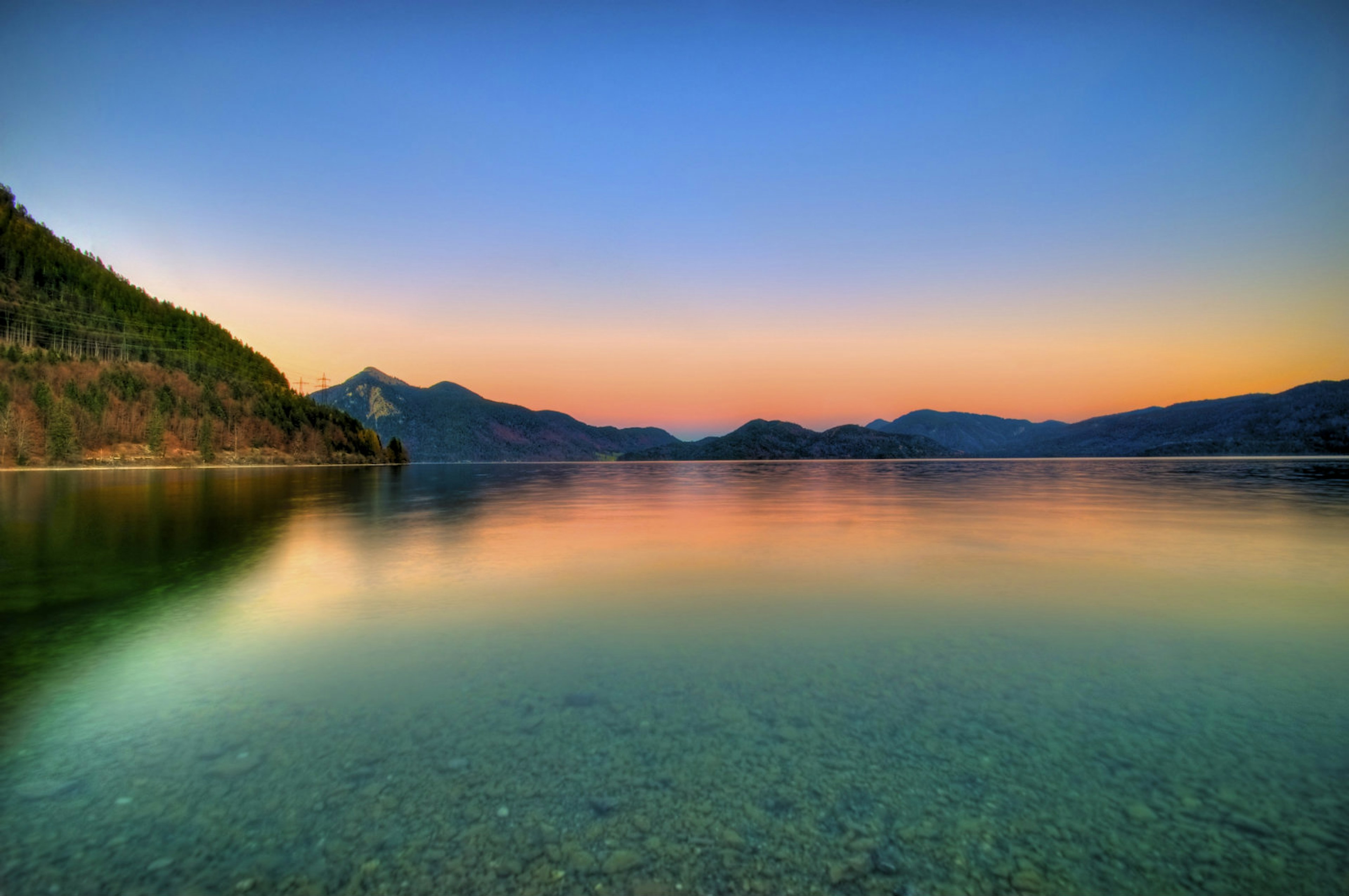 A vast, still lake surrounded by peaks at dusk