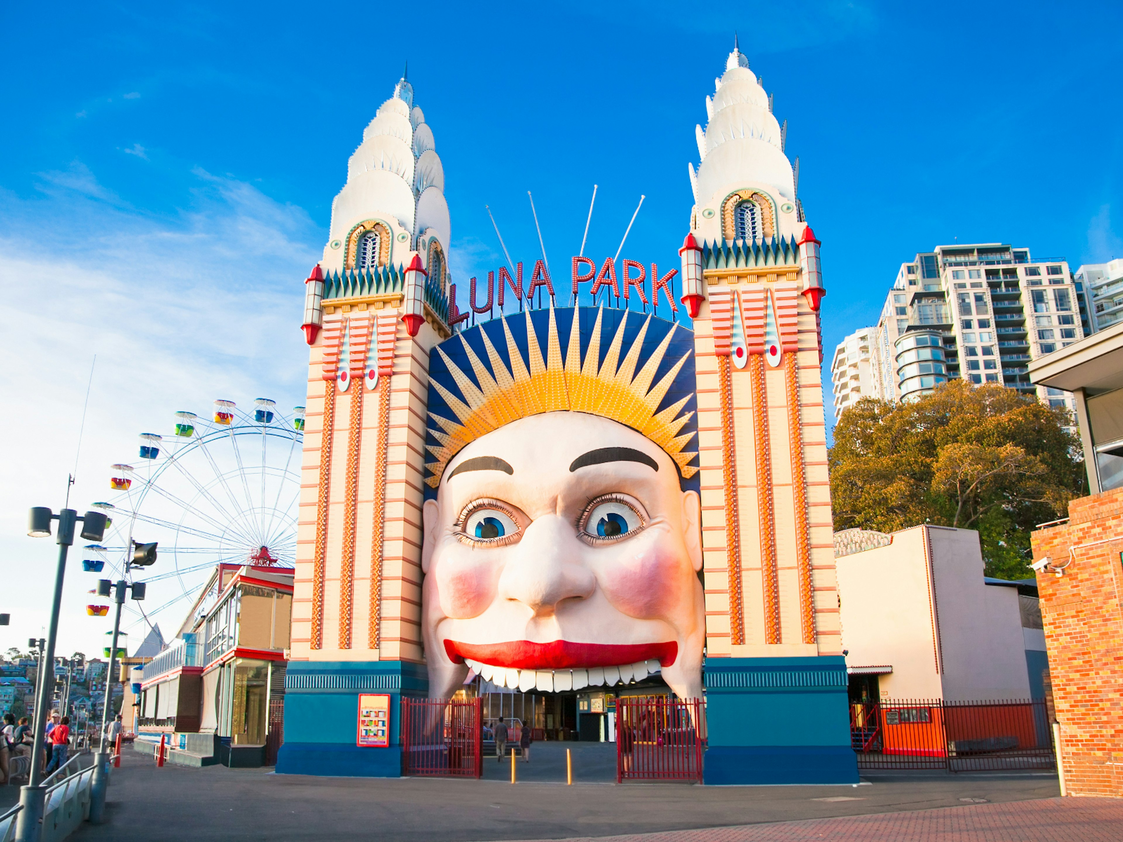 Disney alternatives - Mr Moon, the gatekeeper to a world of adventure at Luna Park. A huge pale face framed by skyscrapers is the entrance to Luna Park - with visitors entering through its mouth