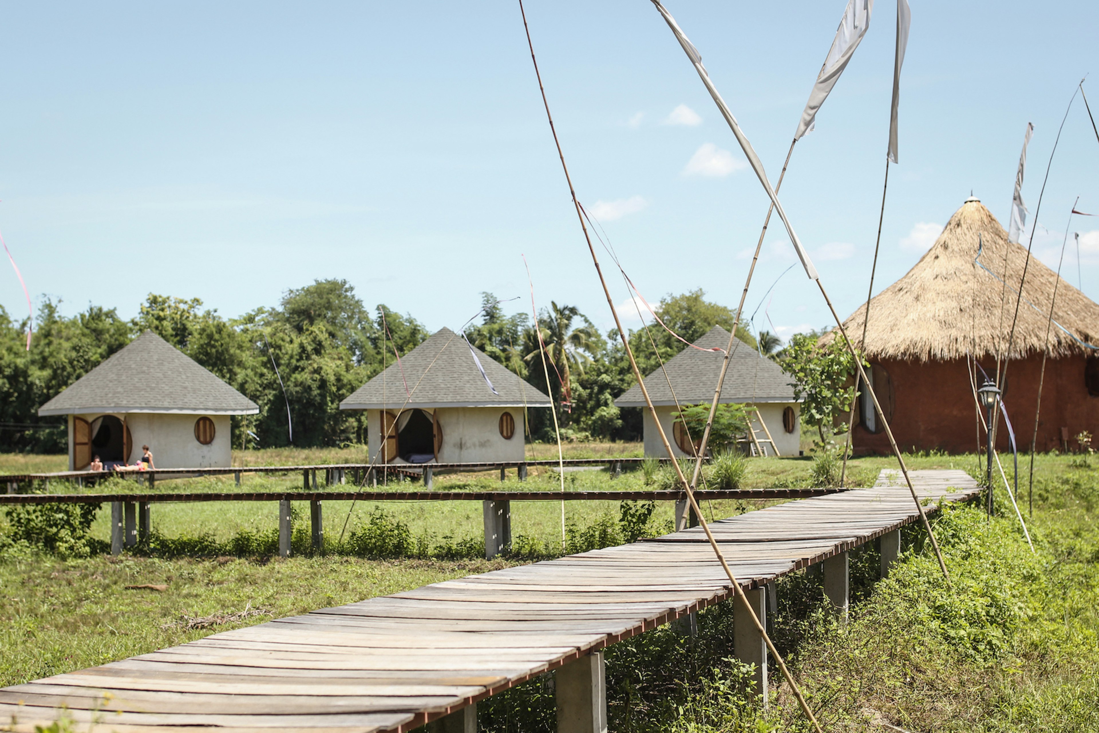 4 huts, one with a thatched roof with a boardwalk path leading to them