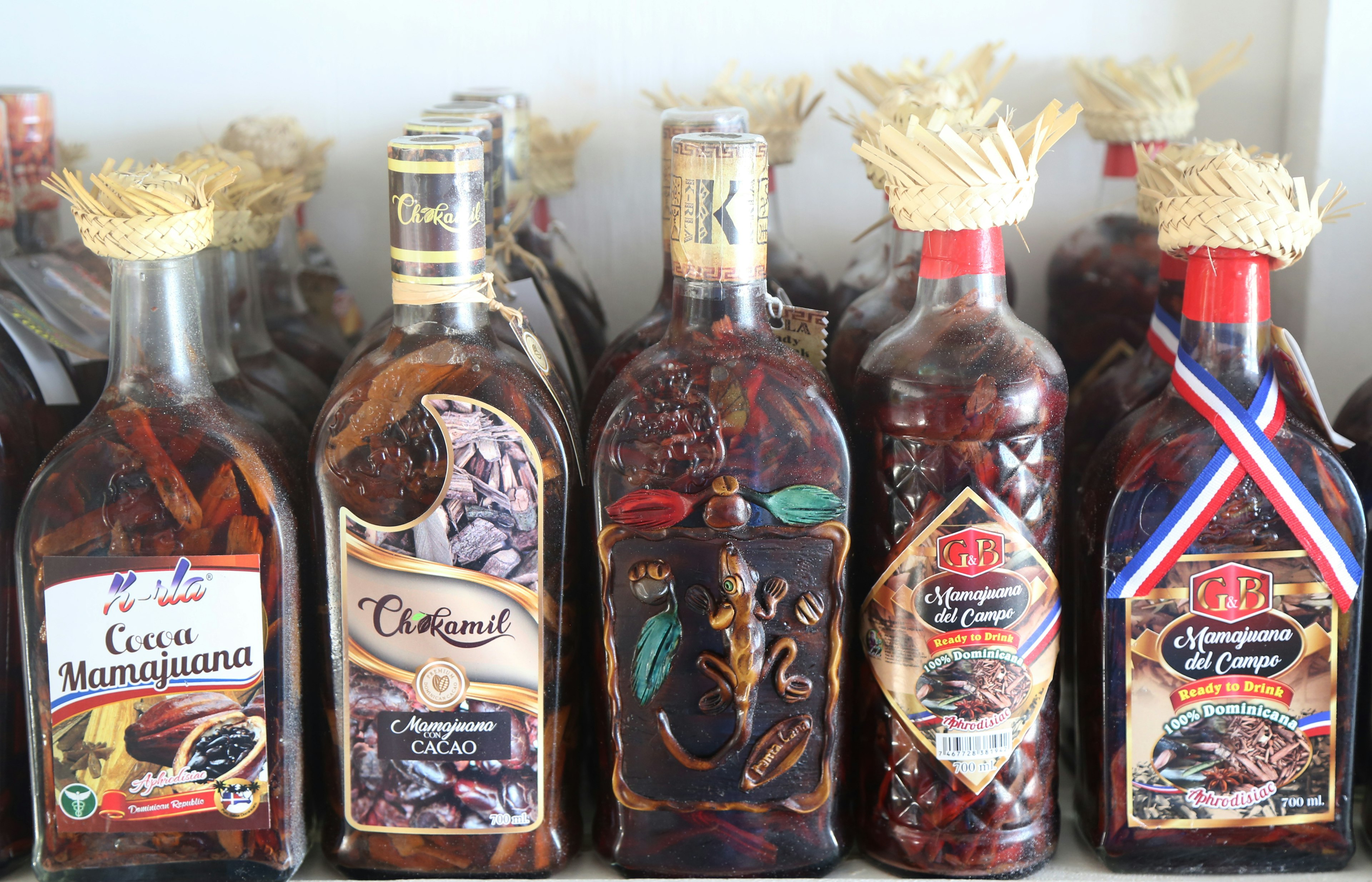 A shelf of assorted bottles each filled with Mama Juana in the Dominican Republic