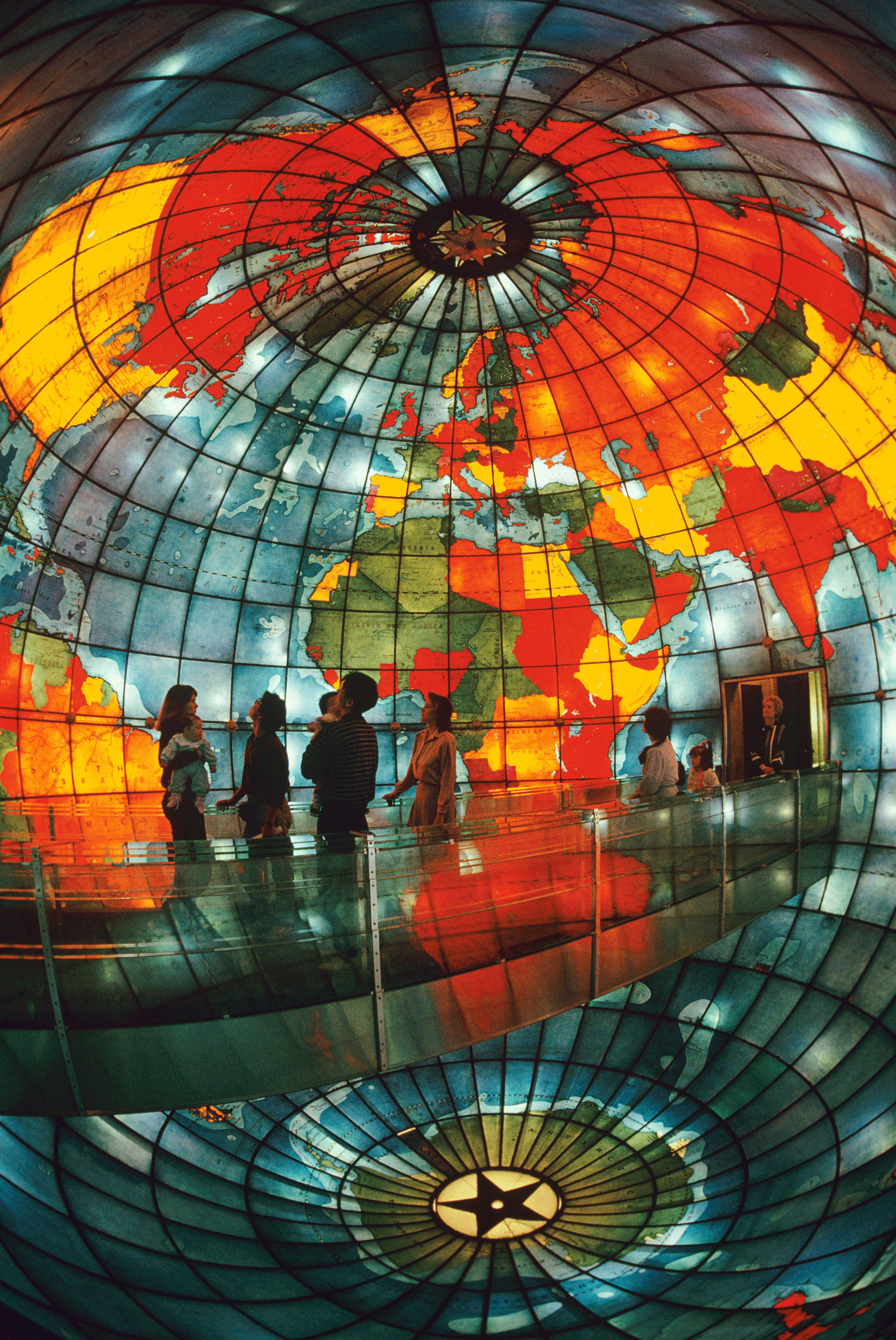 People walk along a bridge in the center of a stained glass glob © Karen Kasmauski / Getty Images