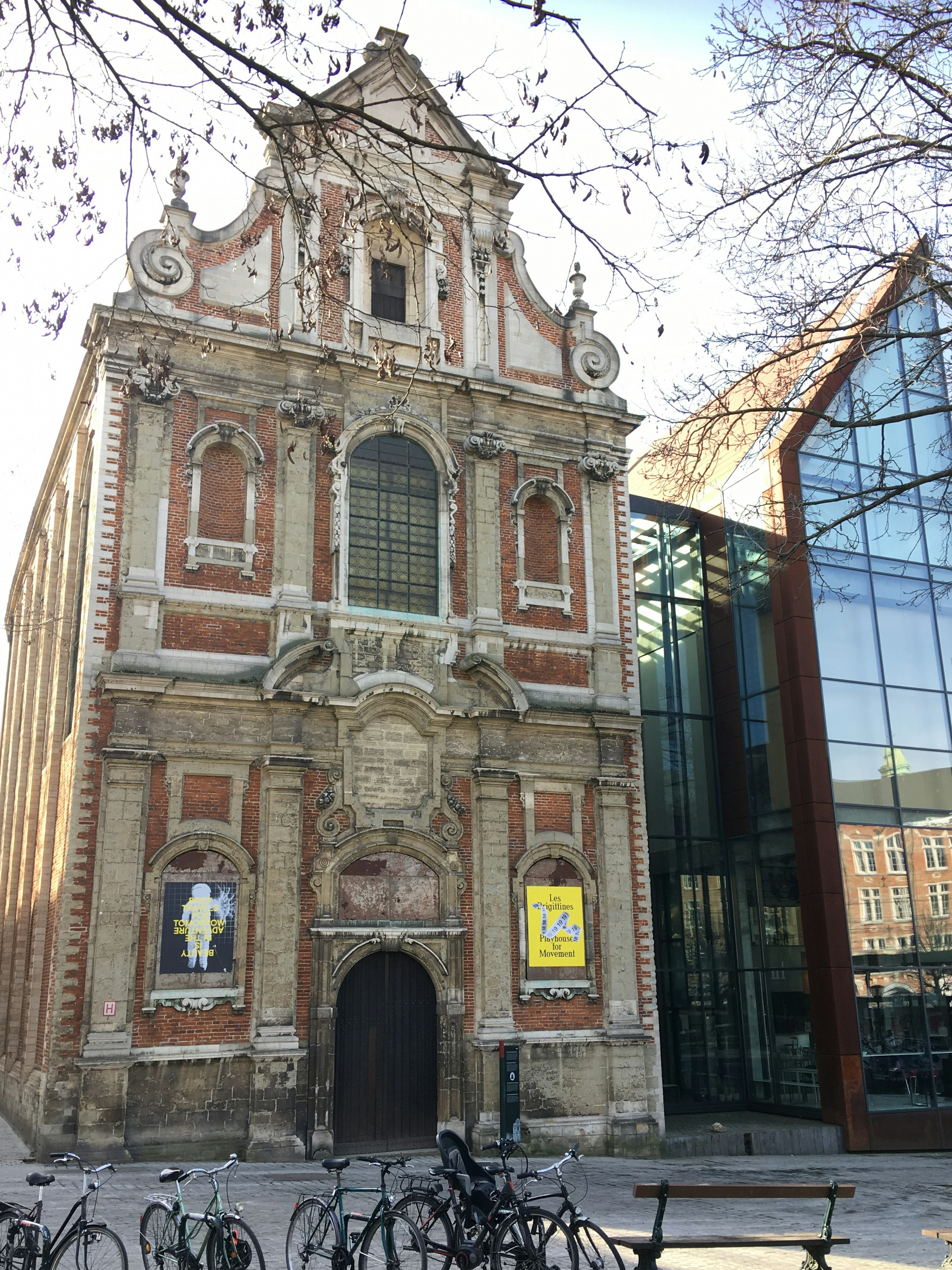 An elaborate Renaissance-style facade made of red brick and grey stone; it has a gabled roof with swirling stone detail, and several of the arched windows are bricked up.