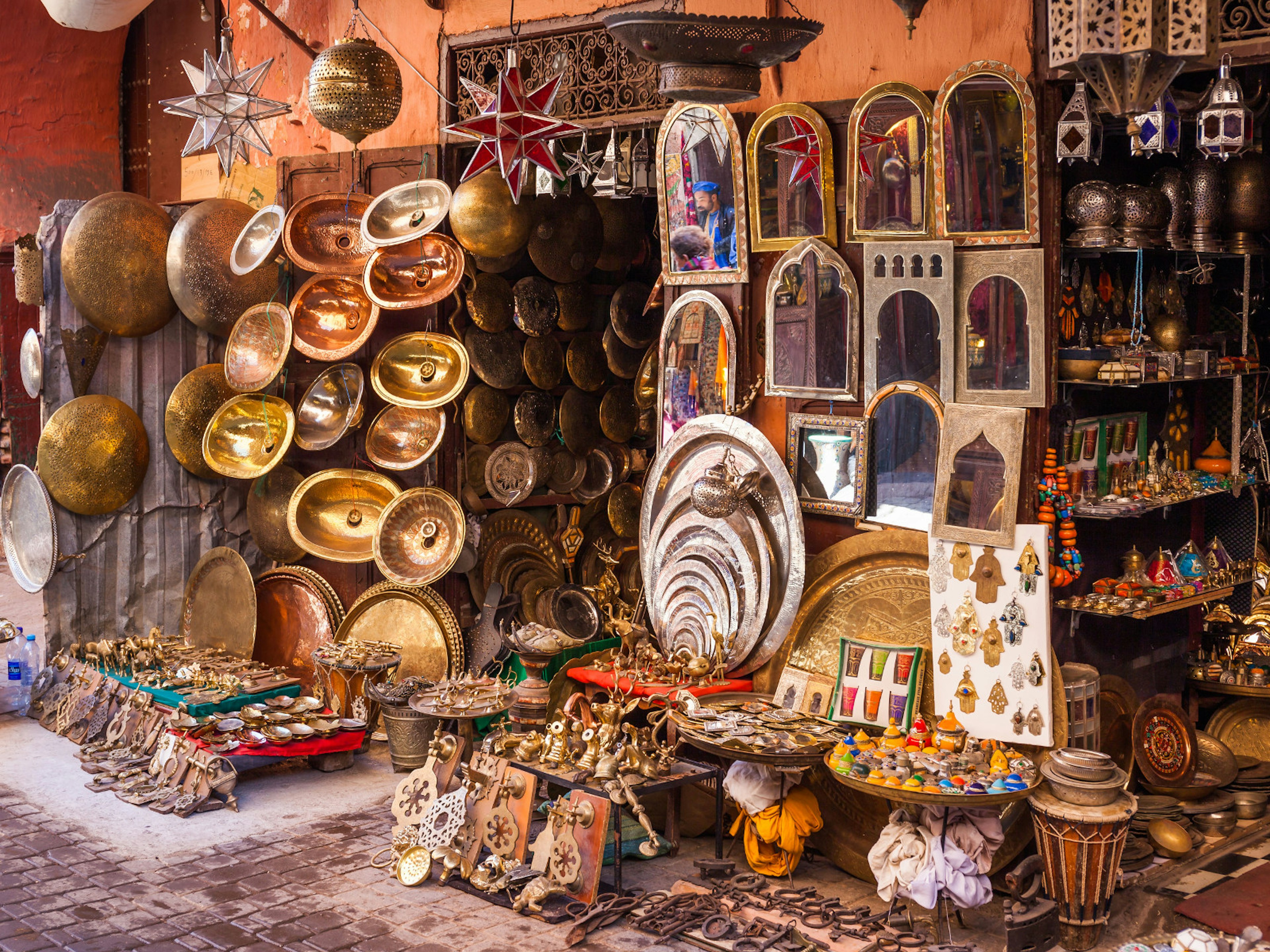 A vendor selling various metalwork items, mirrors and trinkets in a Marrakesh souq