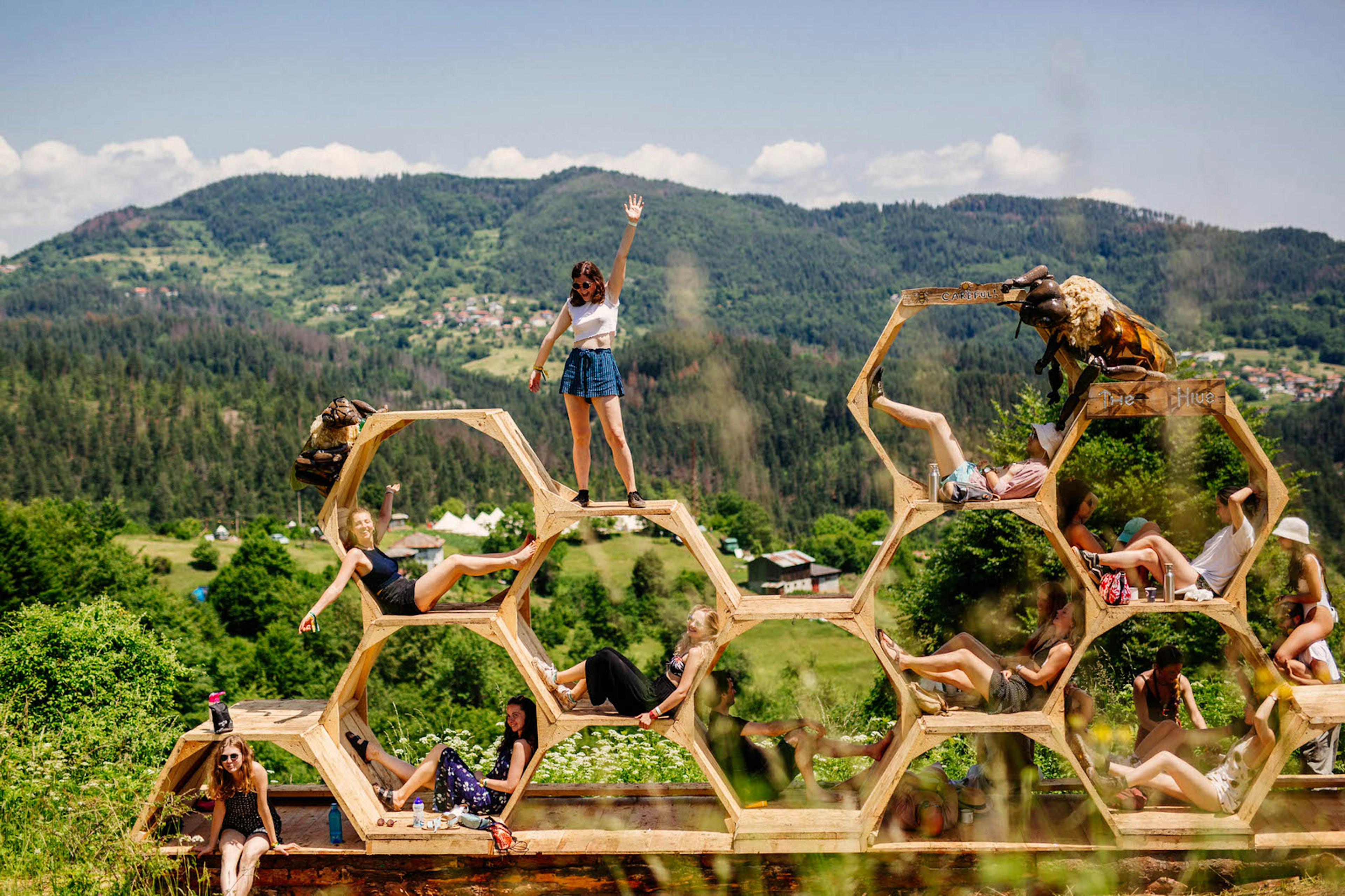 Europe music festival - people pose in and on a honeycomb sculpture in front of a mountain backdrop at Meadows in the Mountains, Bulgaria © Meadows in the Mountains / Aron Klein