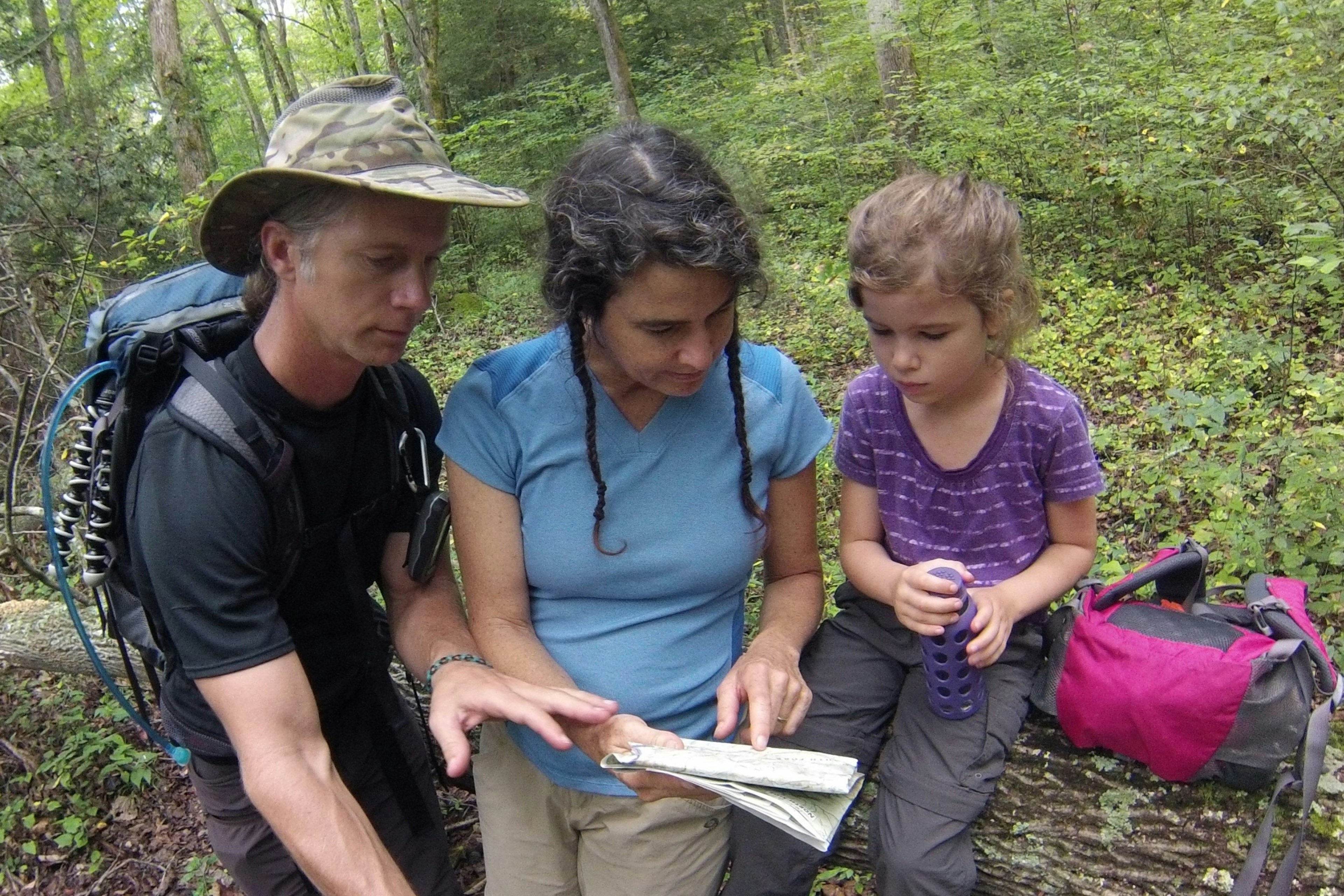 A man and a woman look at a map with their young daughter; Project remote