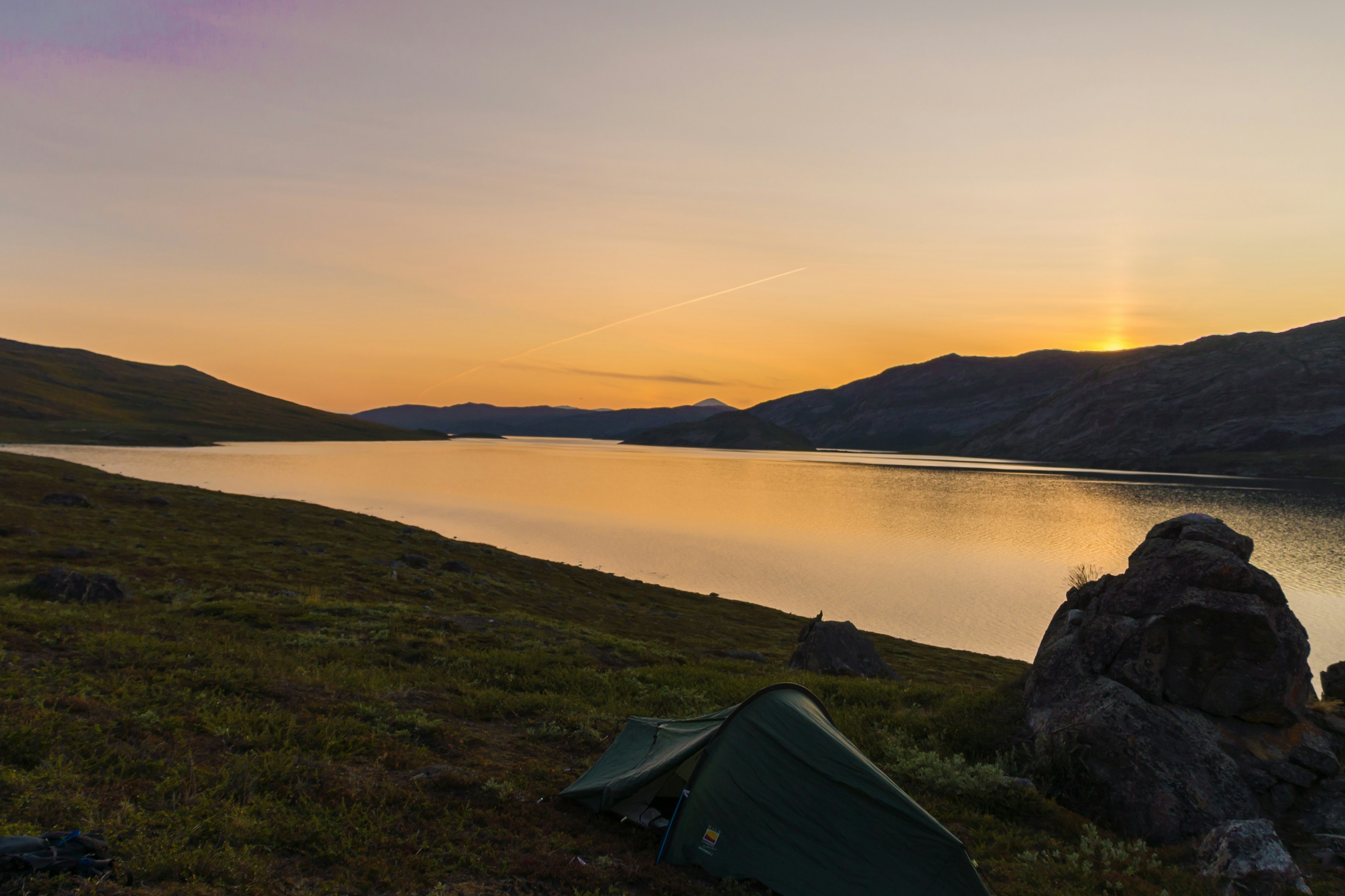 Peter's tent and the lake and mountains beyond under what appears to be a pink-orange sunset.