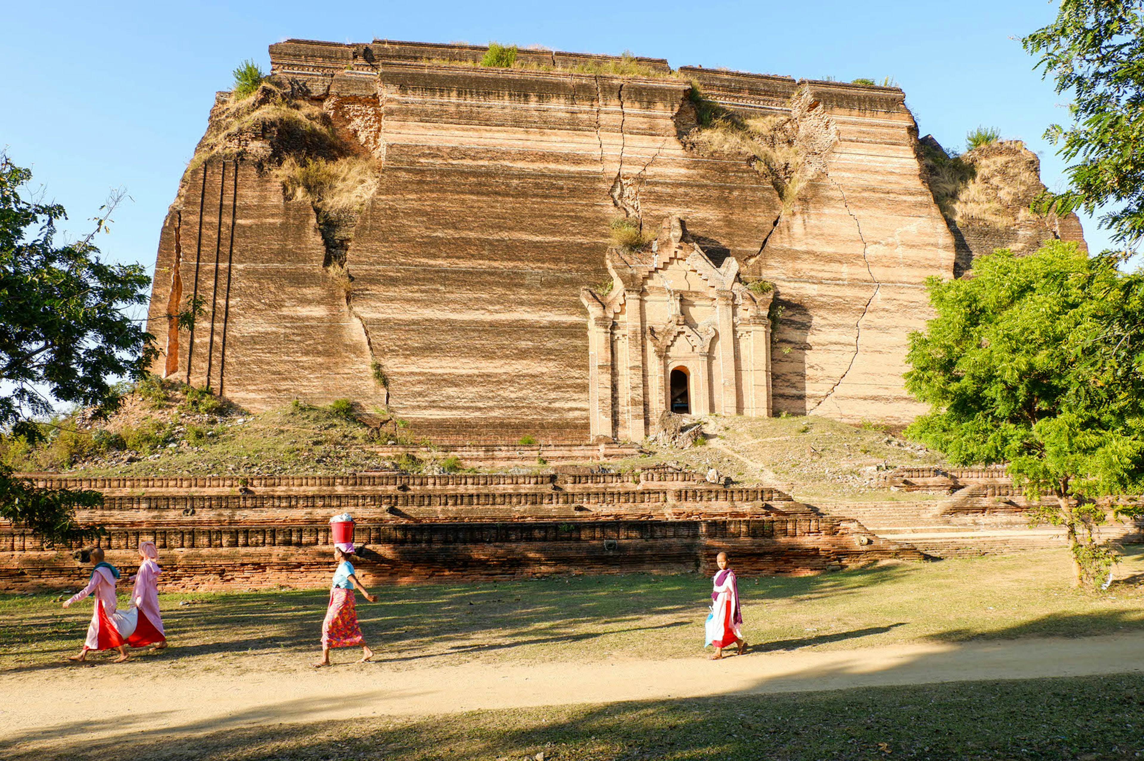 Nuns pass by the enormous unfinished monument of Mingun Paya