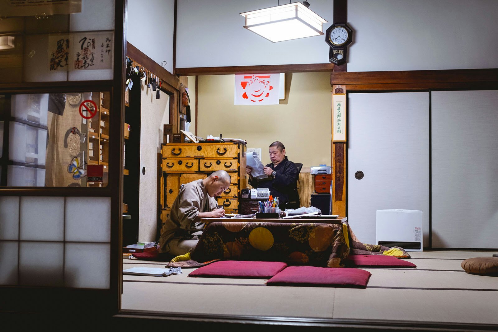 Two monks hunch over paperwork at Eko-in