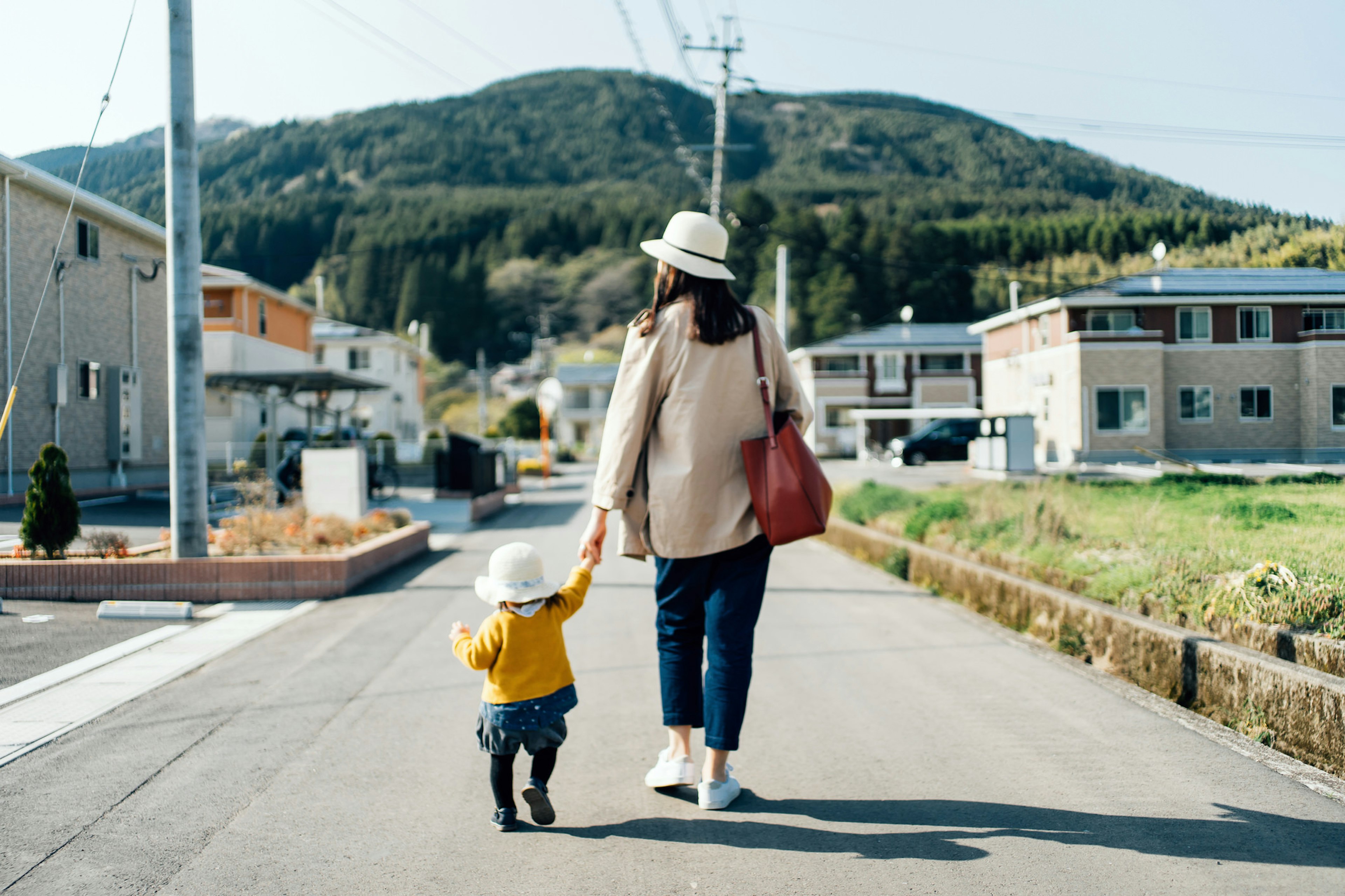 Mother and child, holding hands, walking down the street.