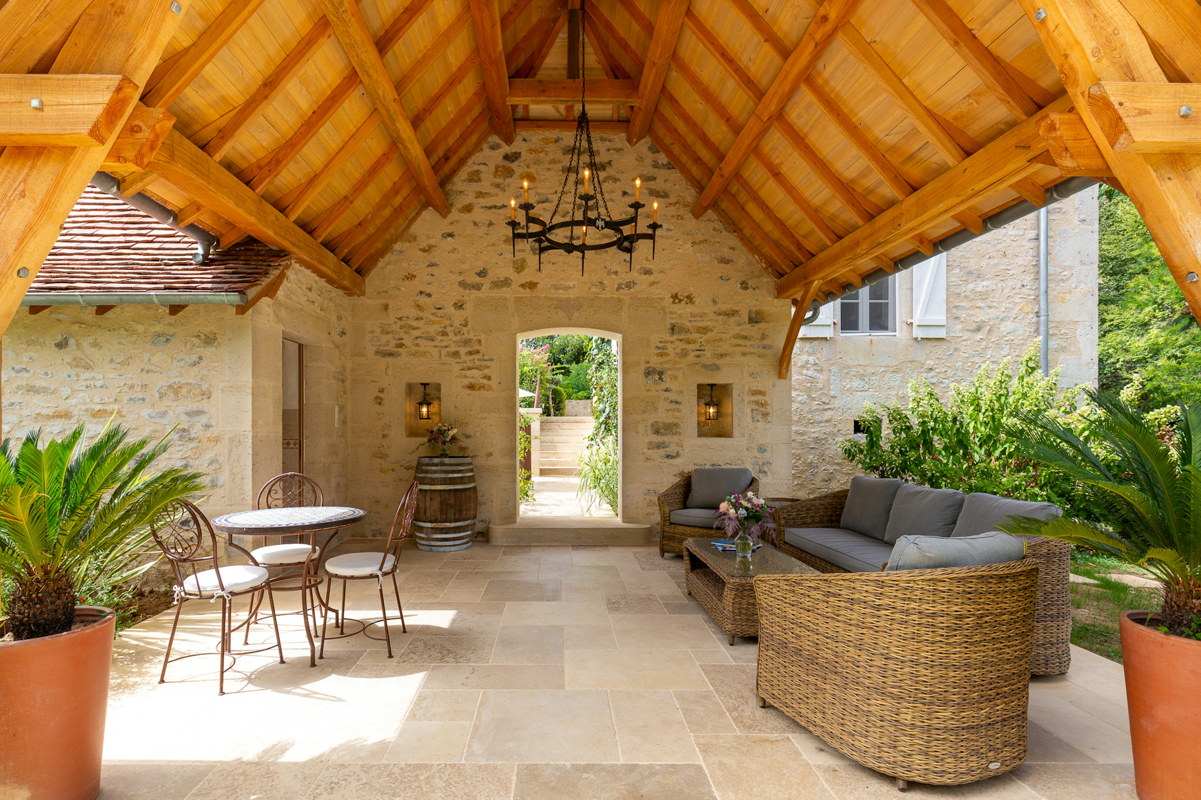 A vaulted roof with wooden slats form a covered walkway with loungers