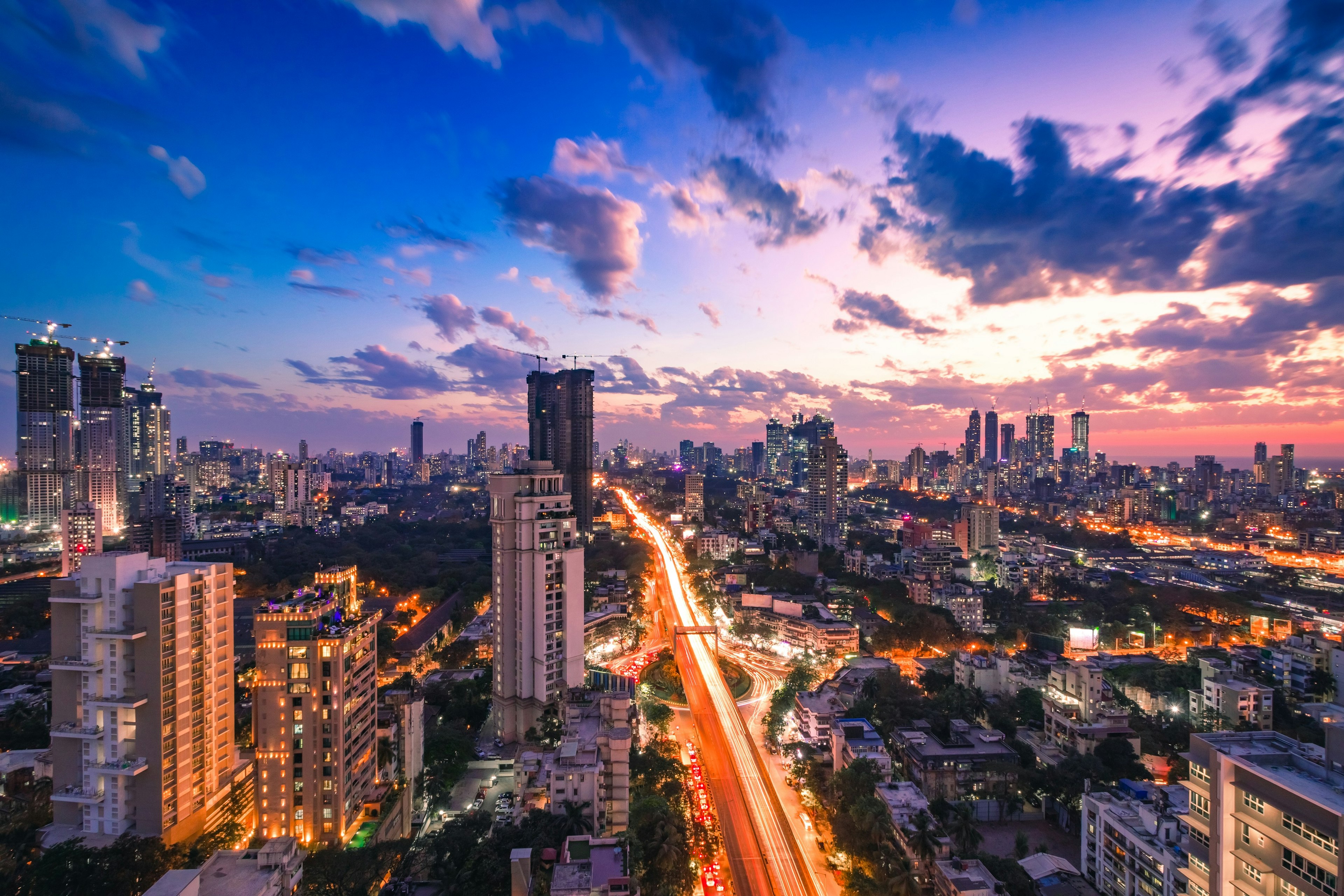 An aerial view of the skyline of Mumbai in the late evening, with the lights from windows, street lamps and cars illuminating the scene.