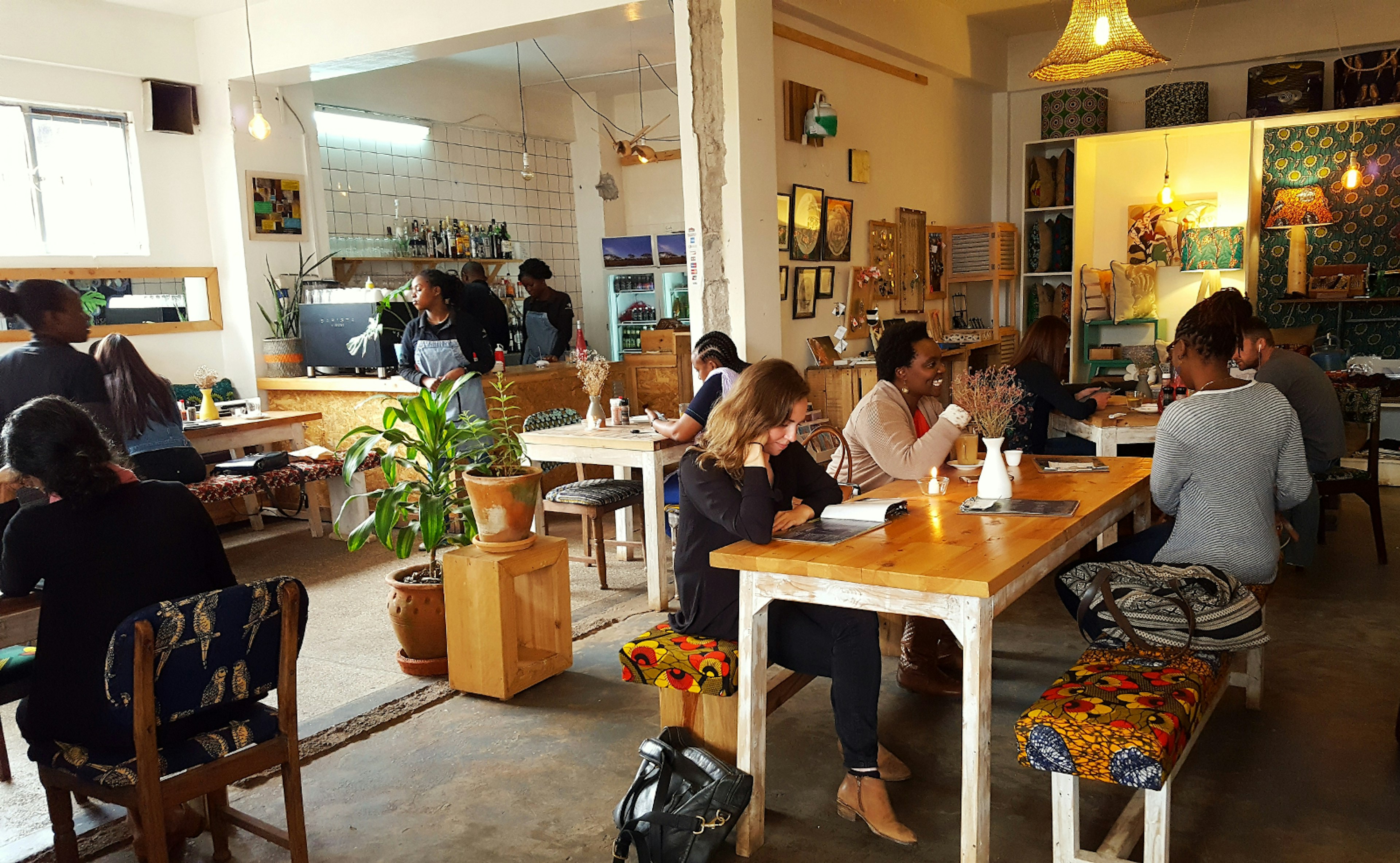 Patrons chat, read magazines and dine. The floors are polished concrete and the tables are shabby chic with benches covered in brightly-coloured African fabrics © Clementine Logan / ϰϲʿ¼