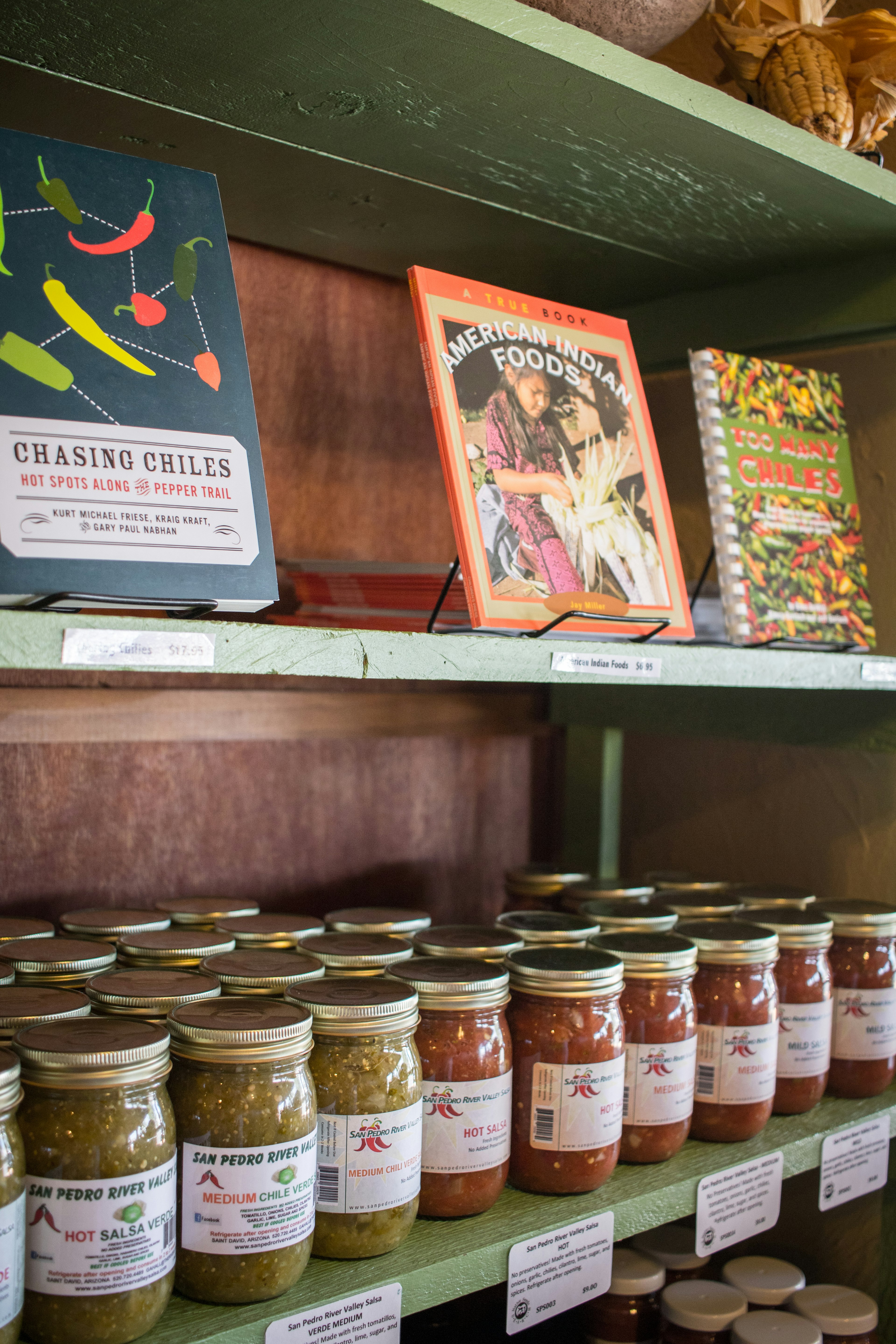 Store shelves with jars of green and red salsas and cookbooks for sale