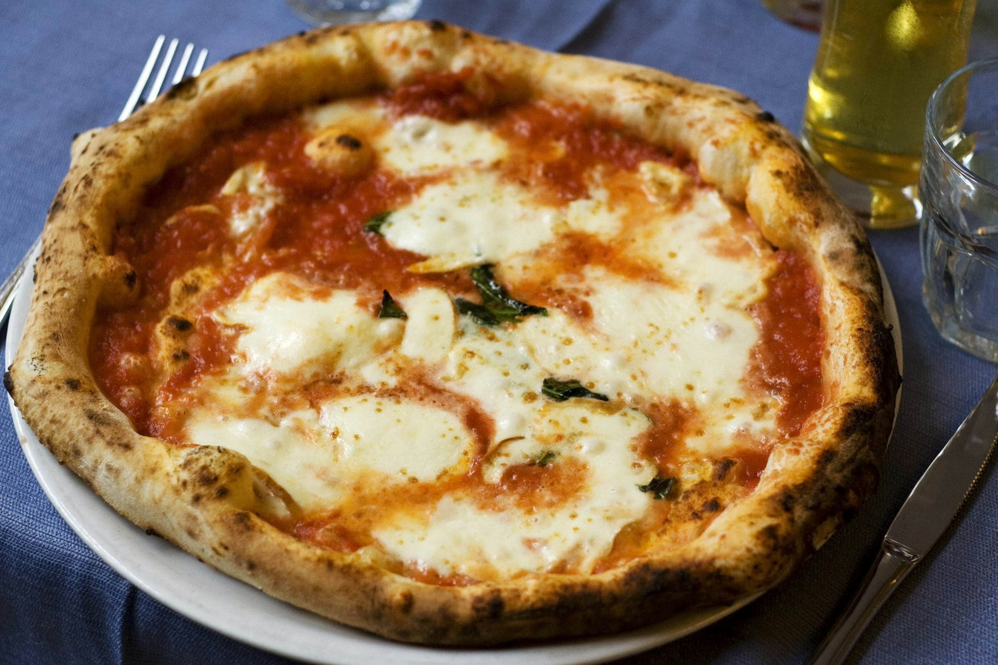 An authentic Neapolitan Pizza Margherita served on a blue woven tablecloth.