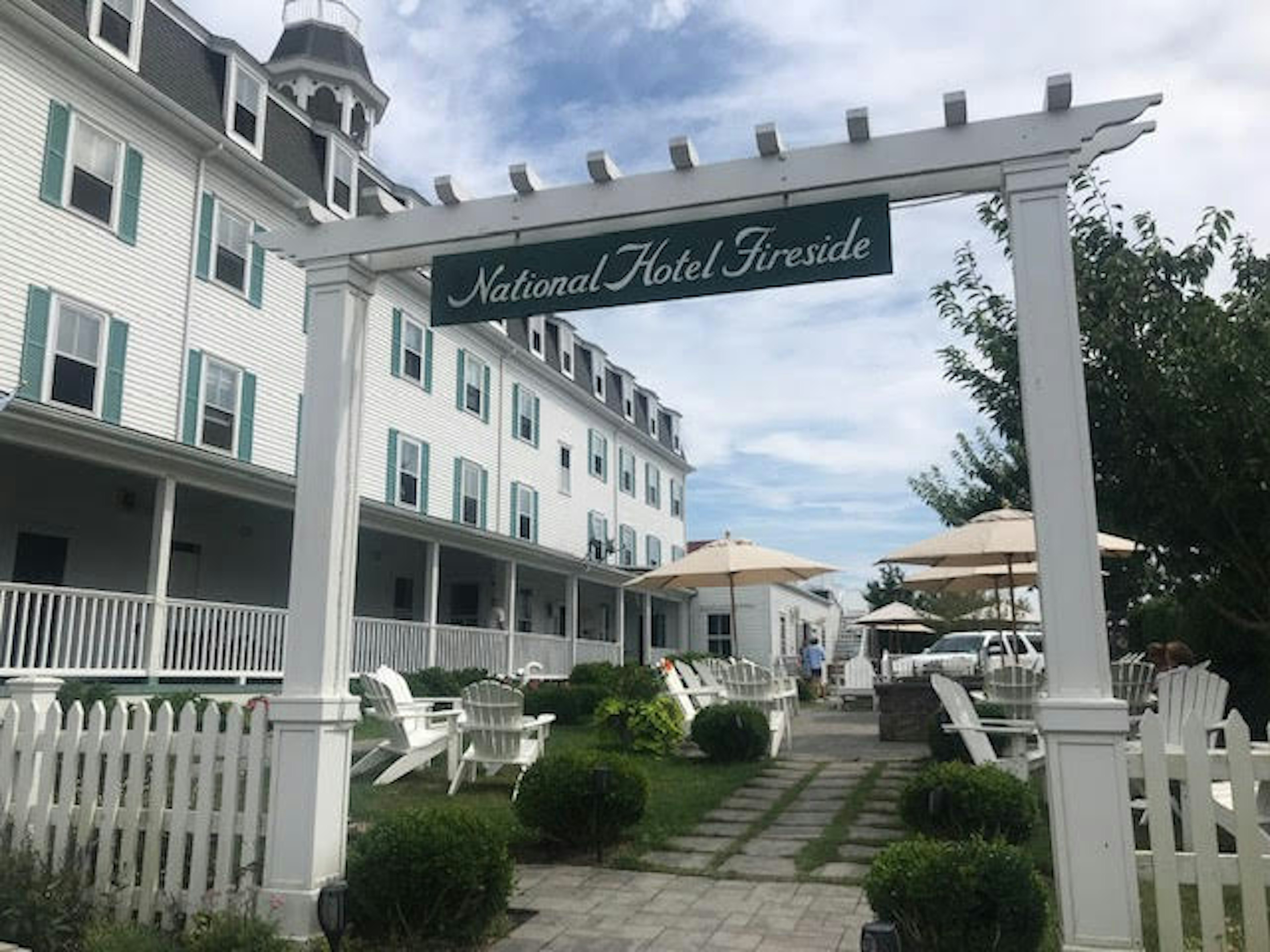 National Hotel Fireside, Block Island. Chairs and parasols are in front of the white building.