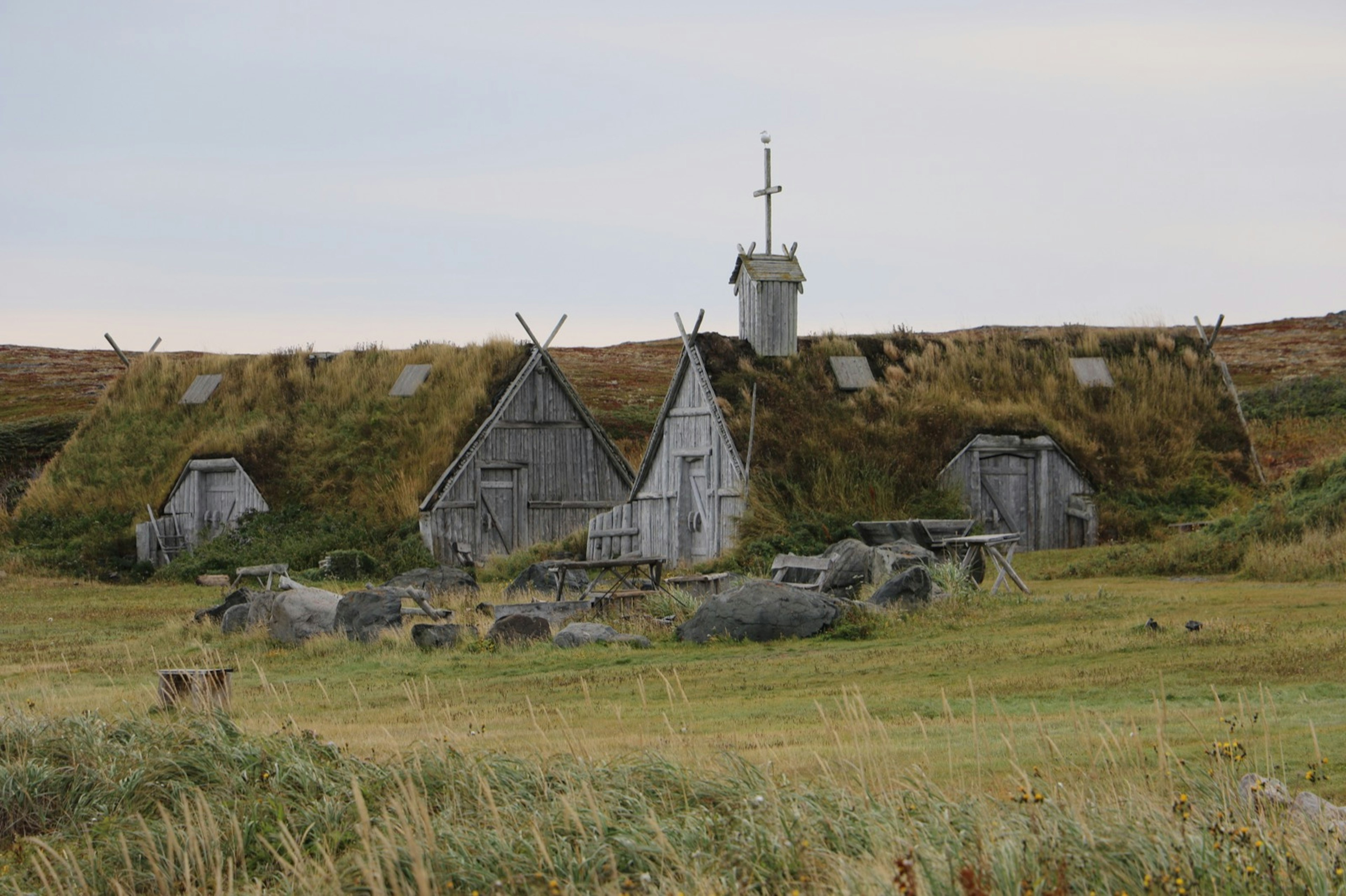 Sod-covered dwellings of grayish wood blend into the surrounding countryside in Newfoundland