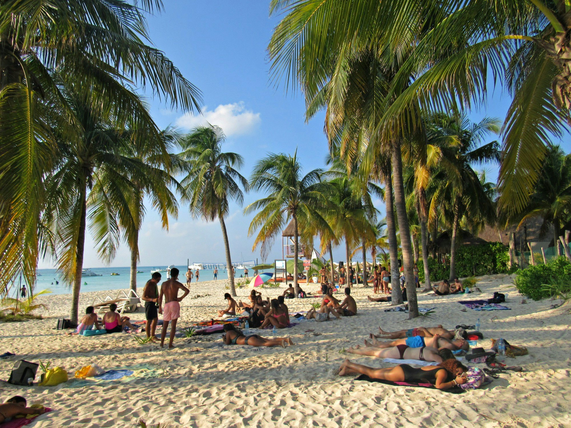 People relax under palm tree on the white sand beaches